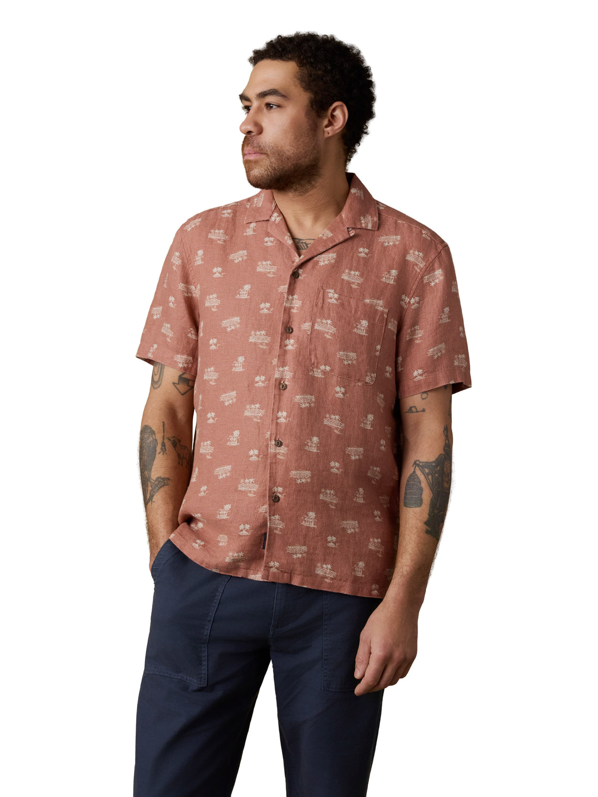 A man wearing a red button up shirt and blue pants, image 1 of 3