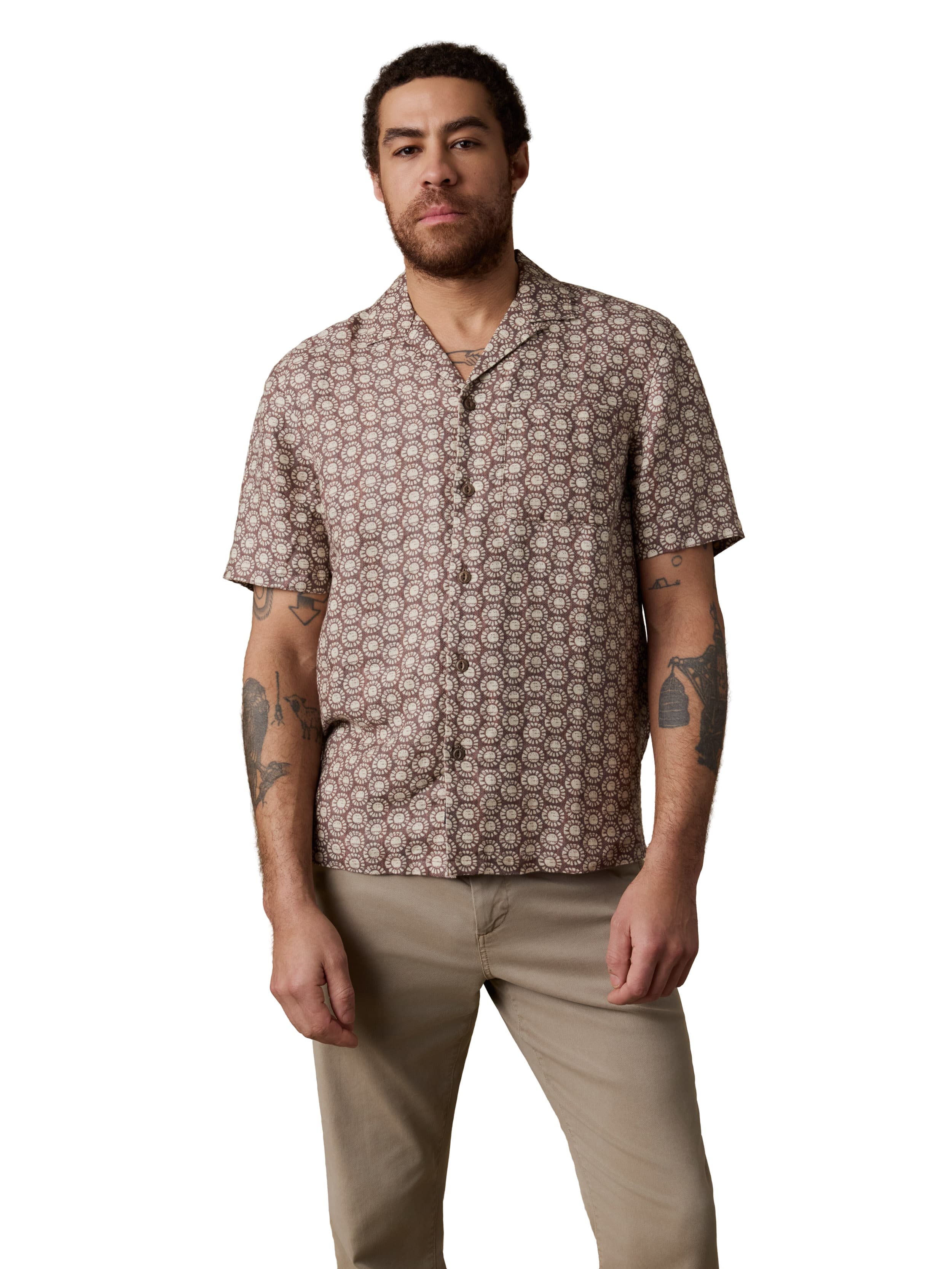 A man wearing a brown printed shirt and beige pants
