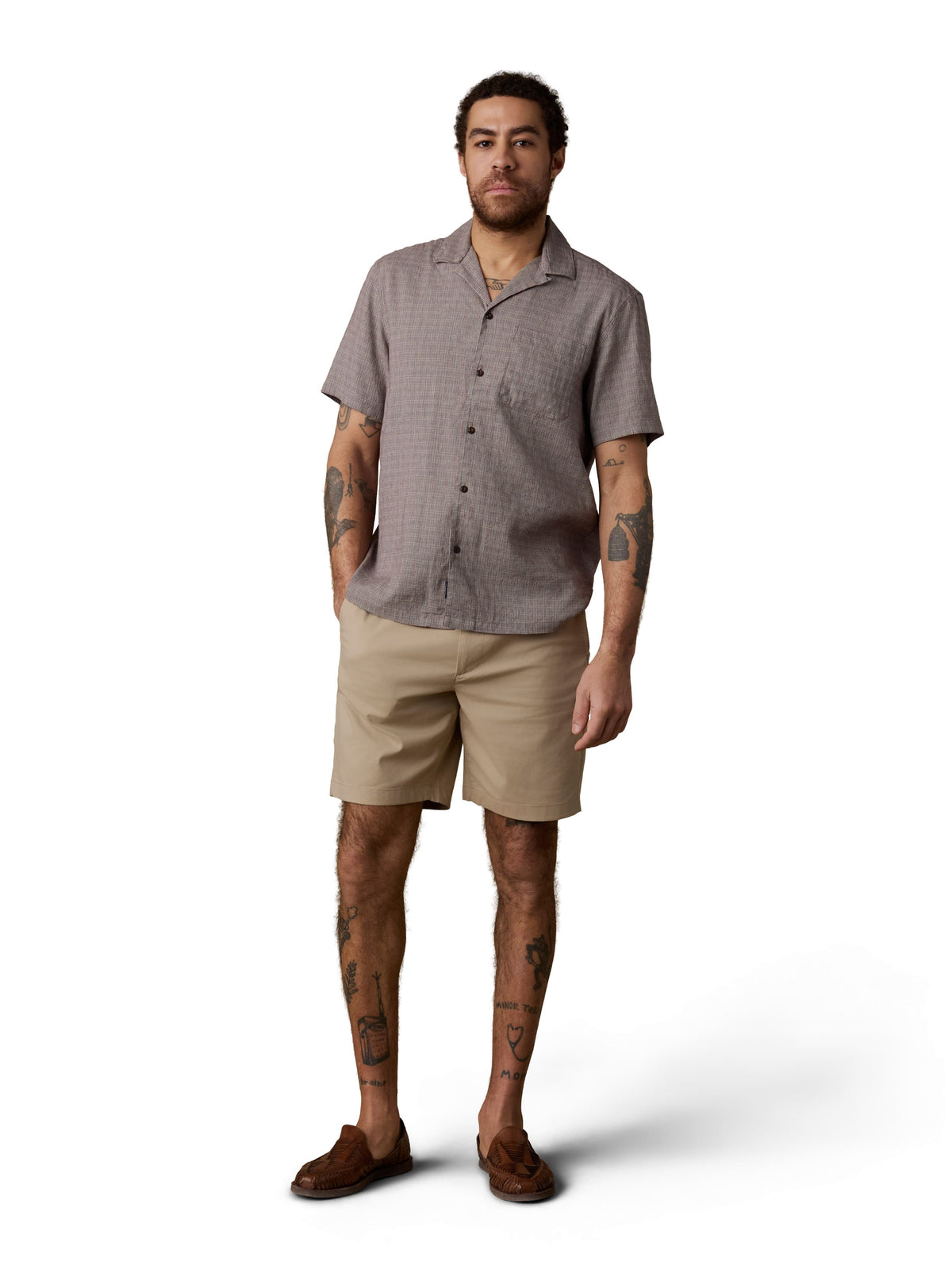 A man wearing a grey shirt, beige shorts, and brown shoes, image 2 of 2