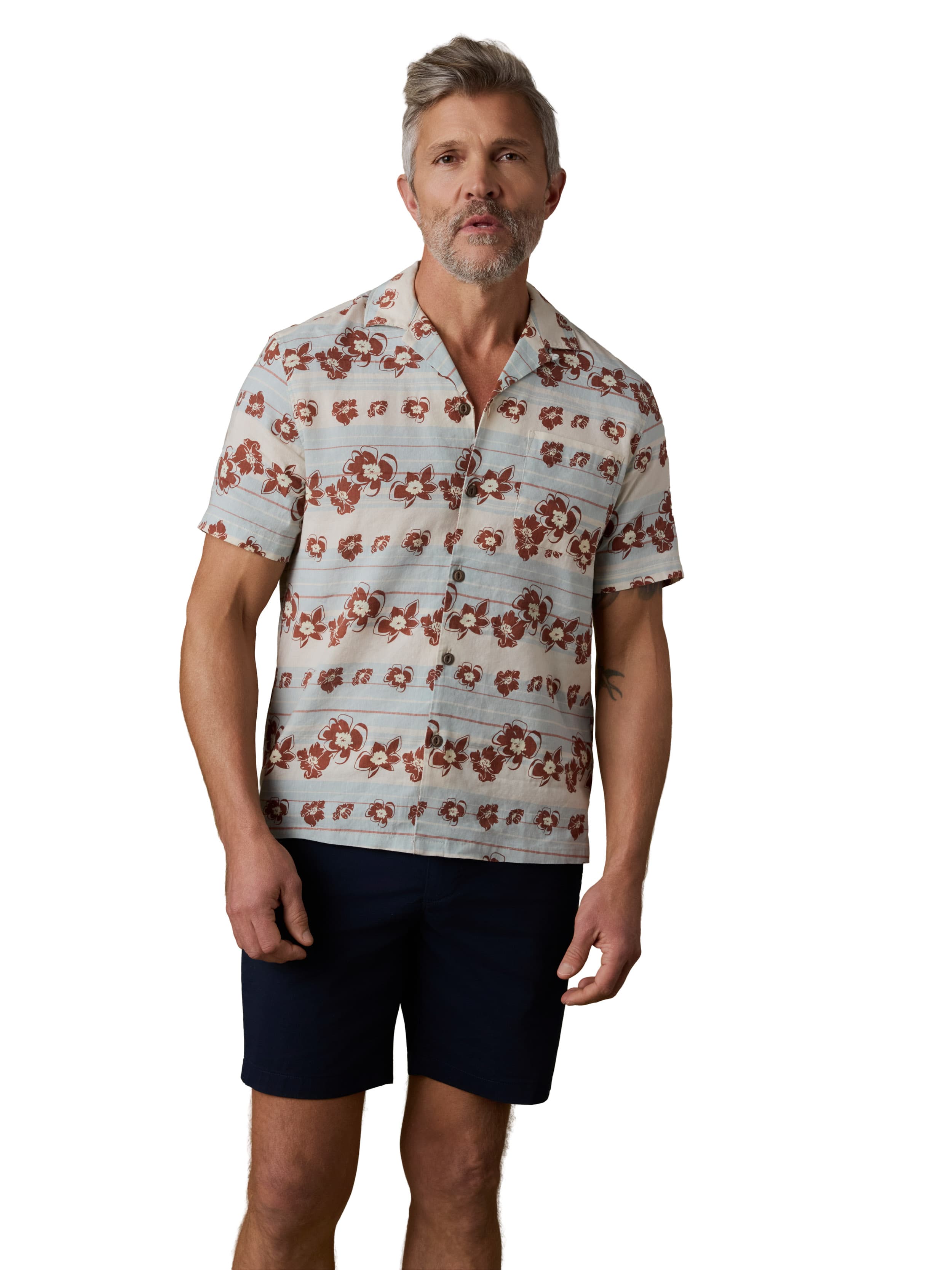 A man wearing a floral printed button up shirt and black shorts