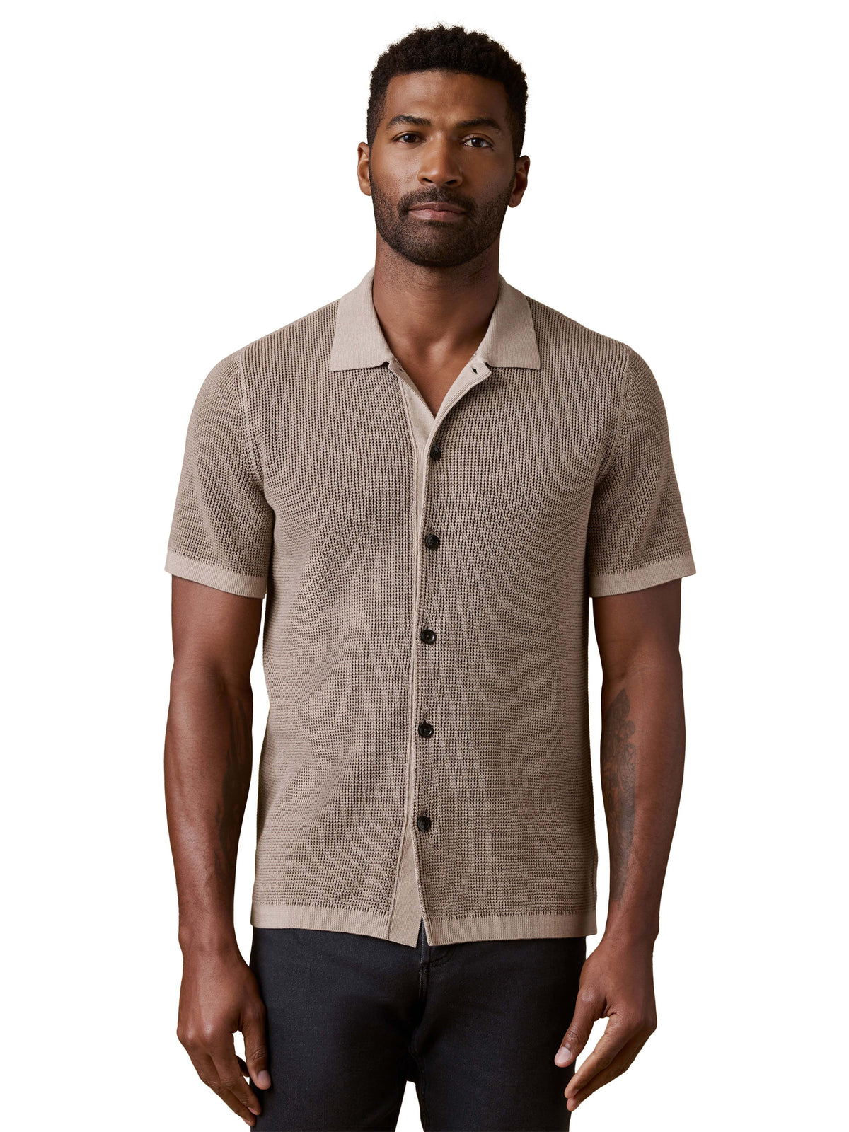 A man wearing a brown polo and dark jeans, image 1 of 3