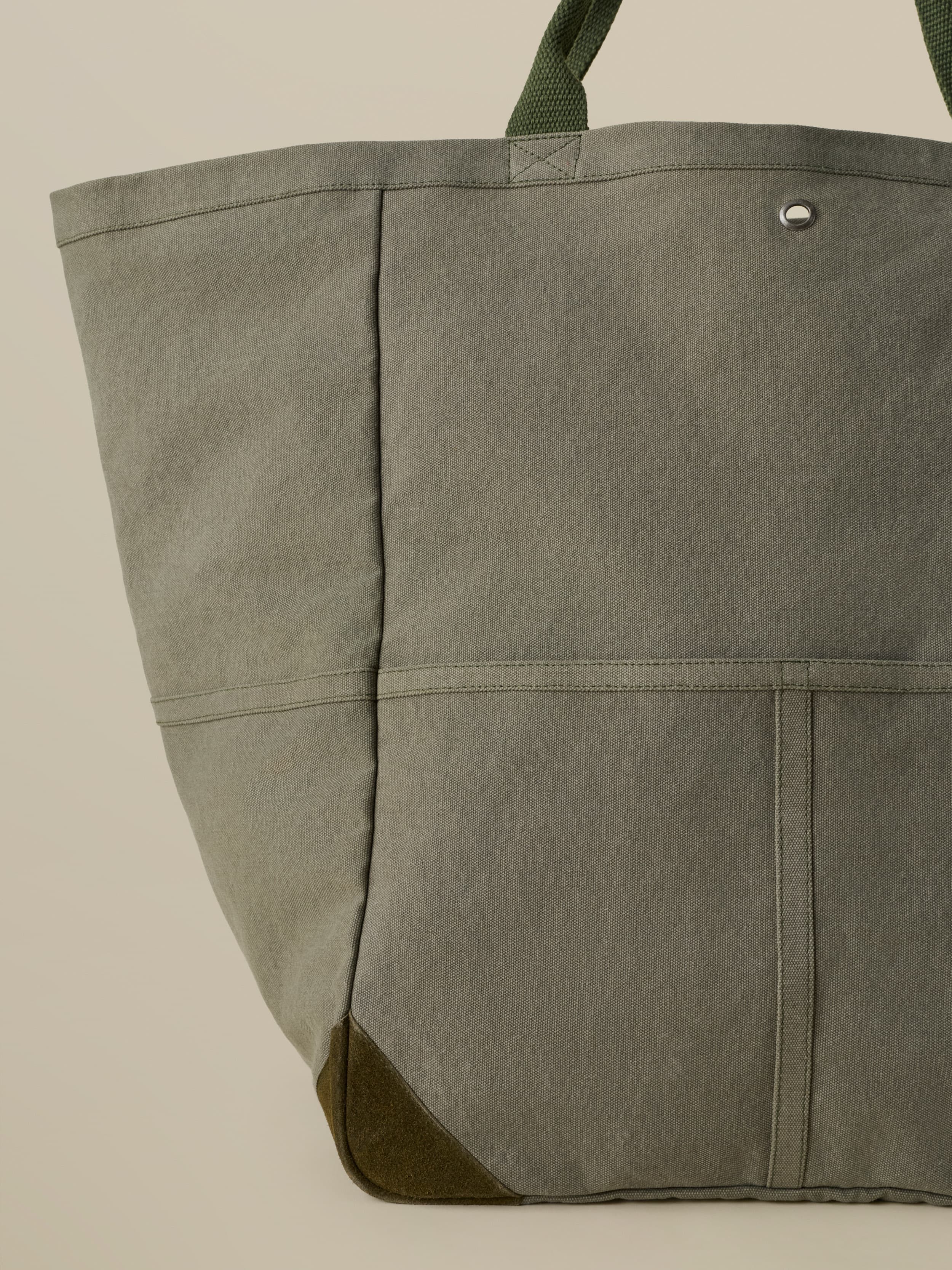 Green tote bag with green suede accents against a beige background