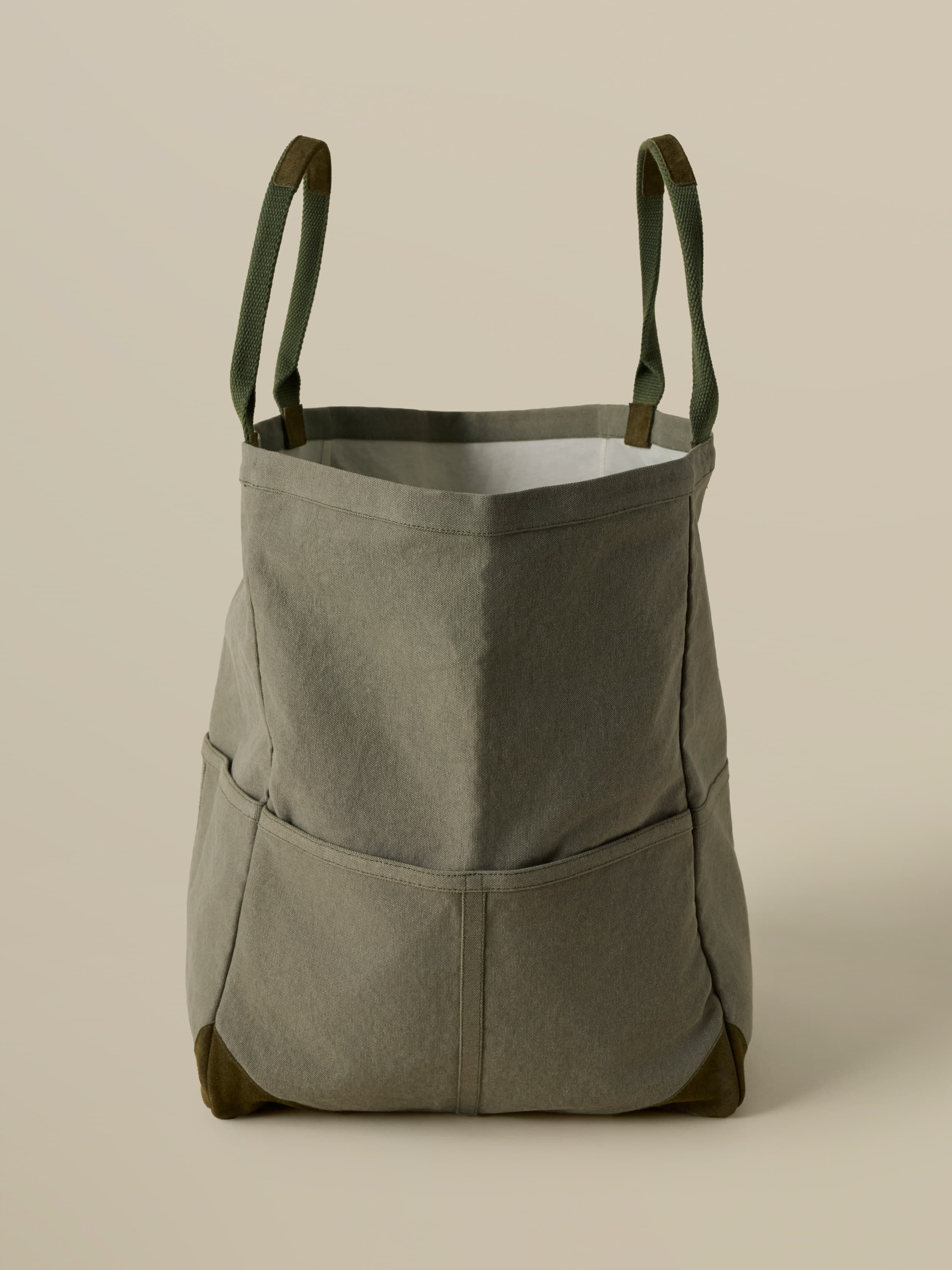 Green tote bag with green straps on a beige background