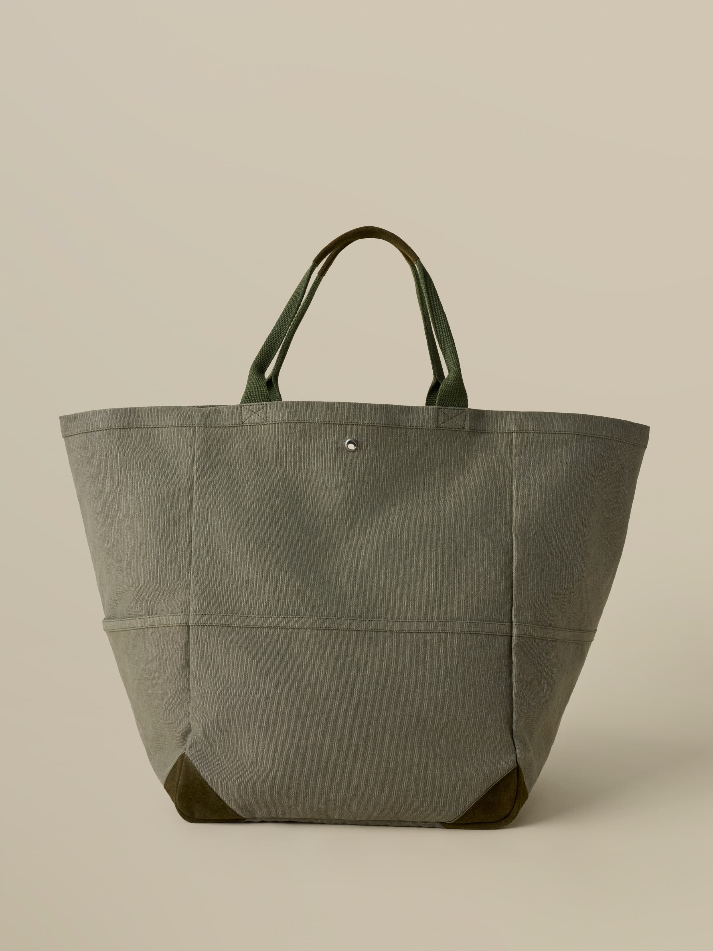 Green tote bag with green handles on a beige background