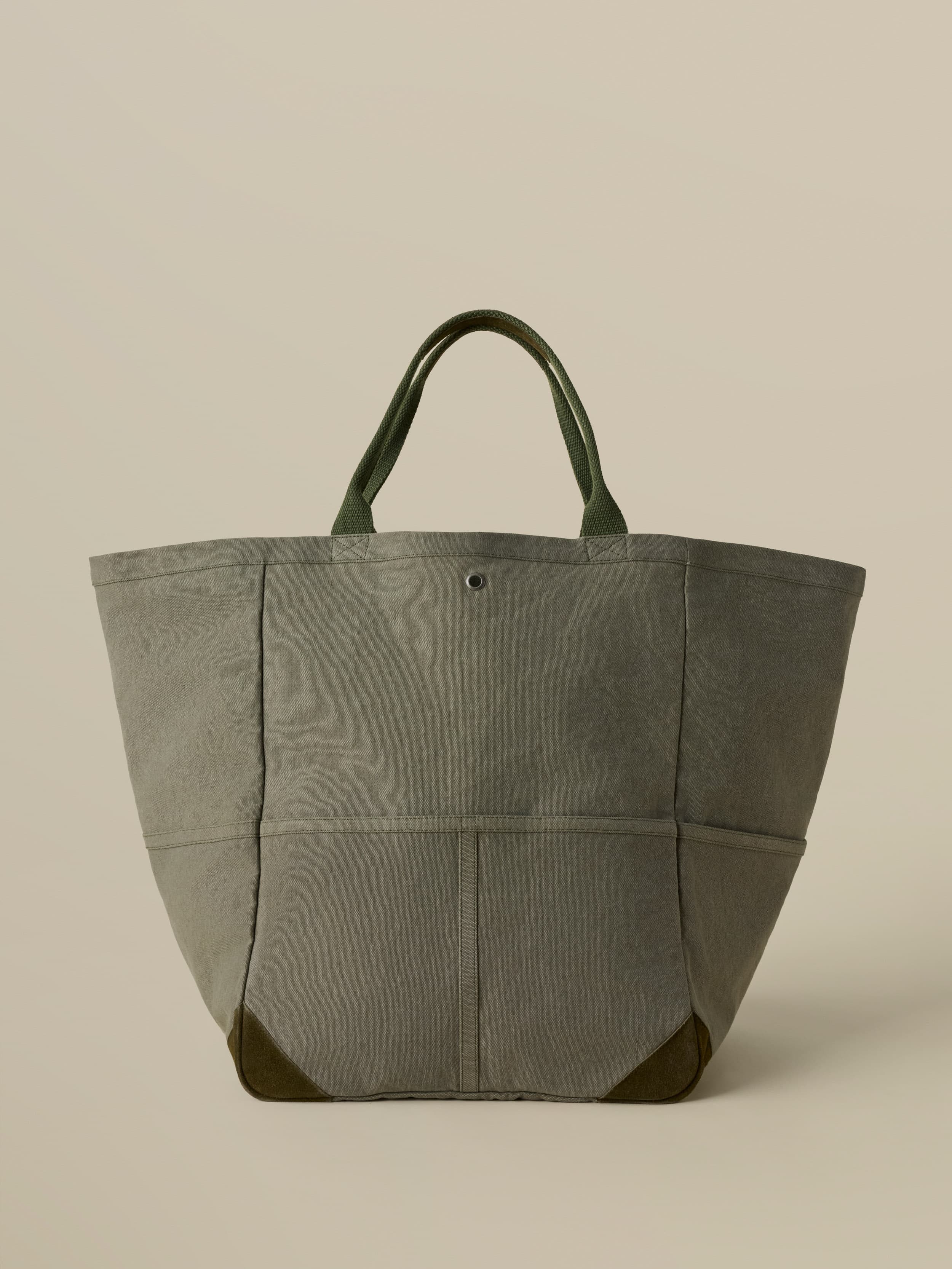 Green tote bag with green handles on a beige background