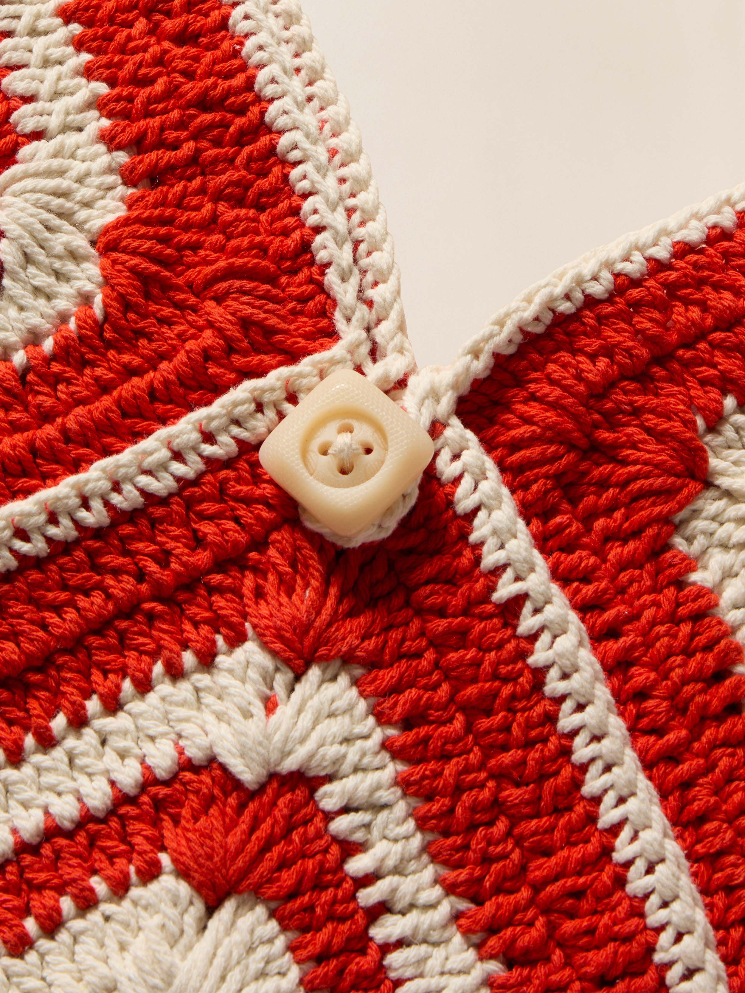 Close-up of a red and white crocheted bag with a button in the center.