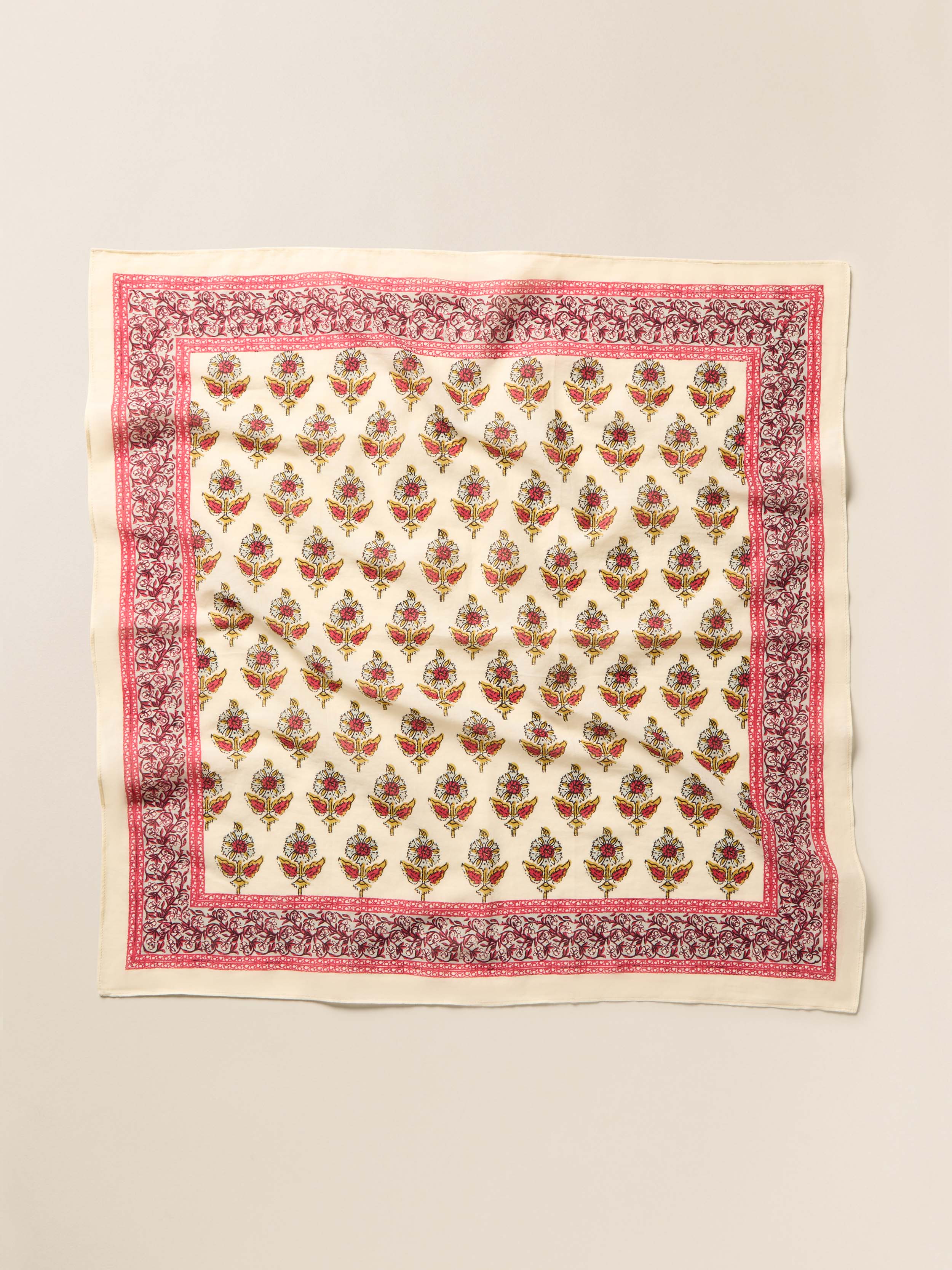 Square bandana with floral pattern and pink border on a beige background