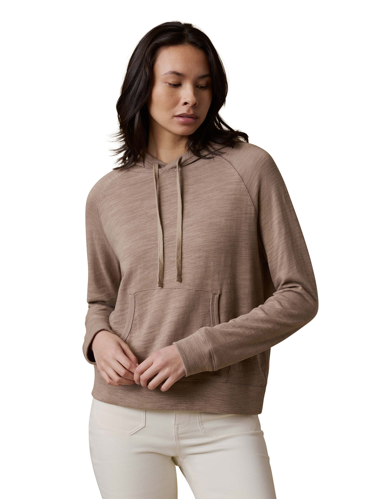 A woman wearing a beige hoodie and white pants, image 1 of 3