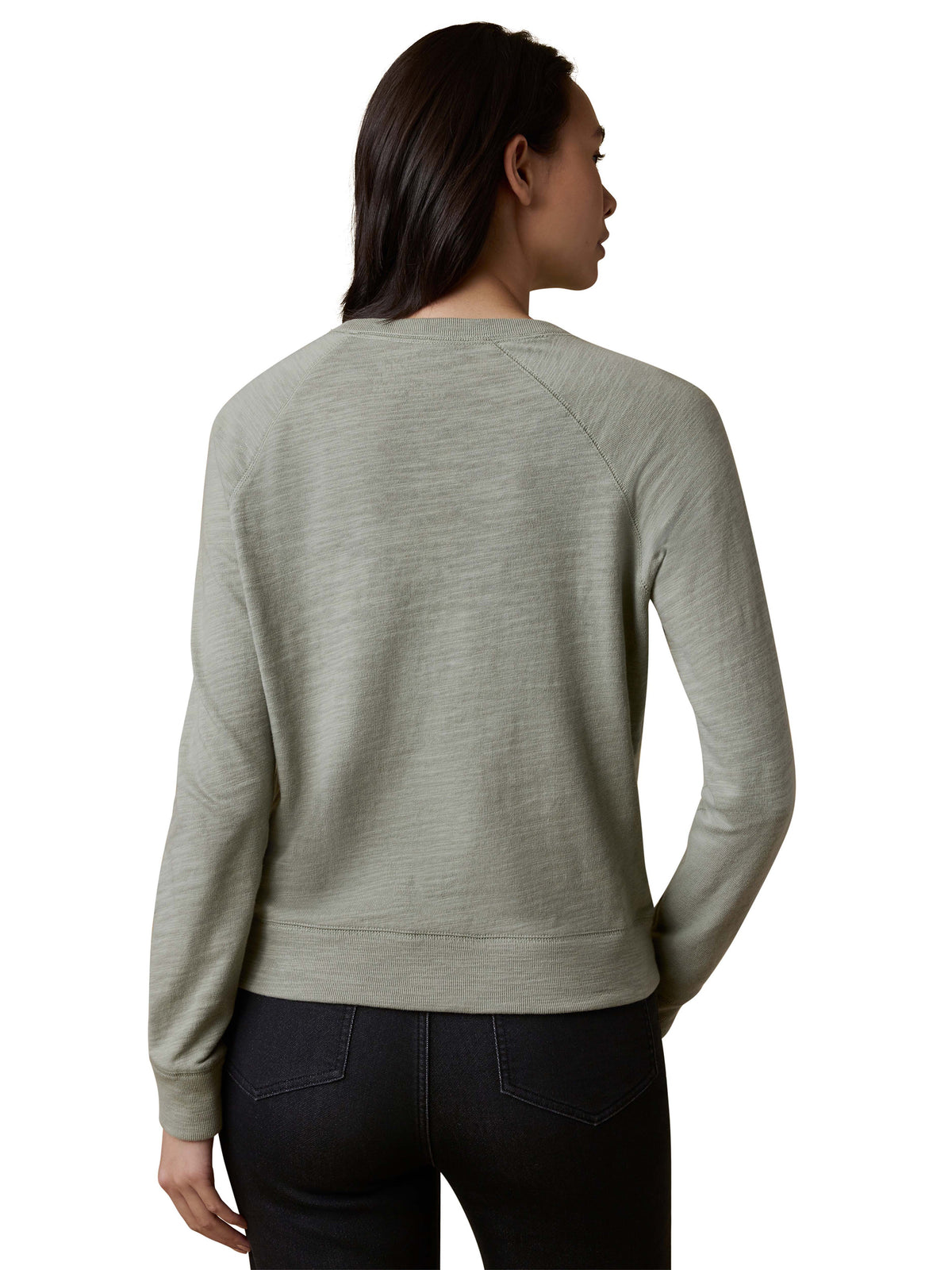 A woman viewed from the back wearing a sage green crewneck and dark jeans, image 3 of 3