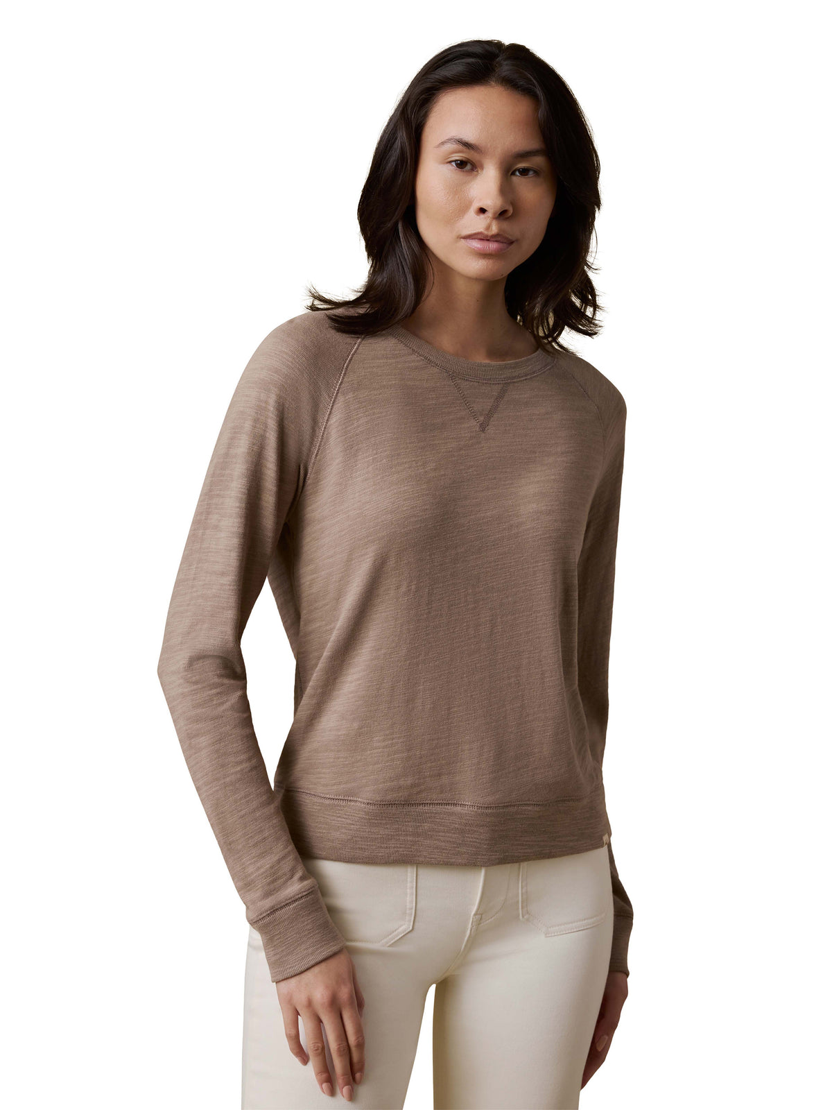 A woman wearing a beige crewneck and white pants, image 1 of 3