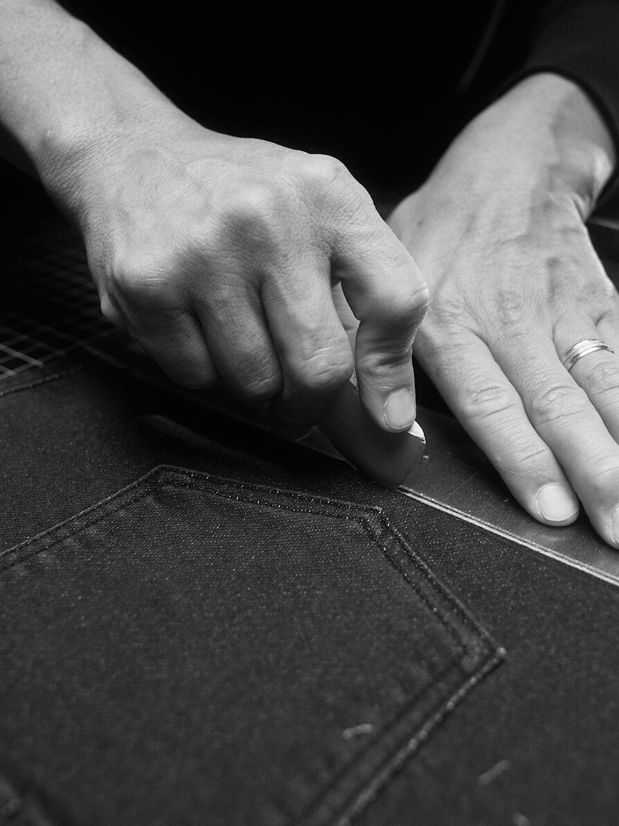 Hands of fashion designer scoring sample of stretch terry pants before cutting