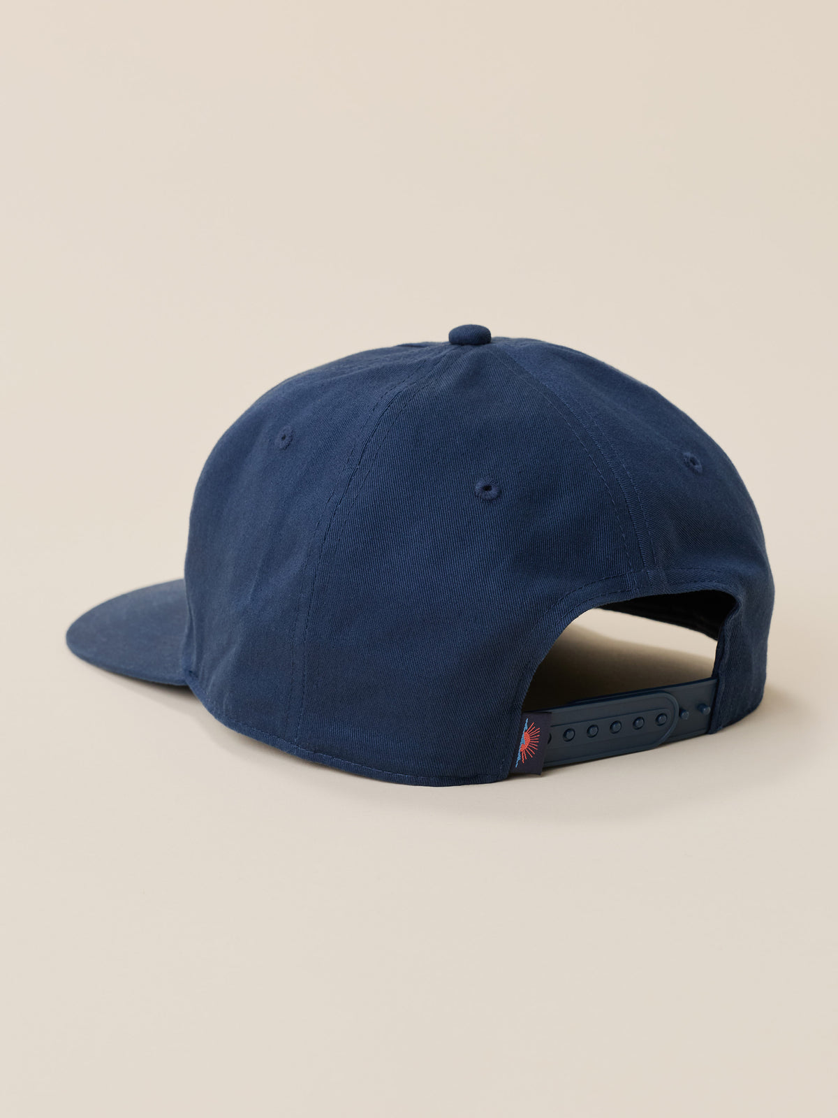 A navy blue baseball cap shown from a rear three-quarter angle on a solid beige background., image 3 of 3