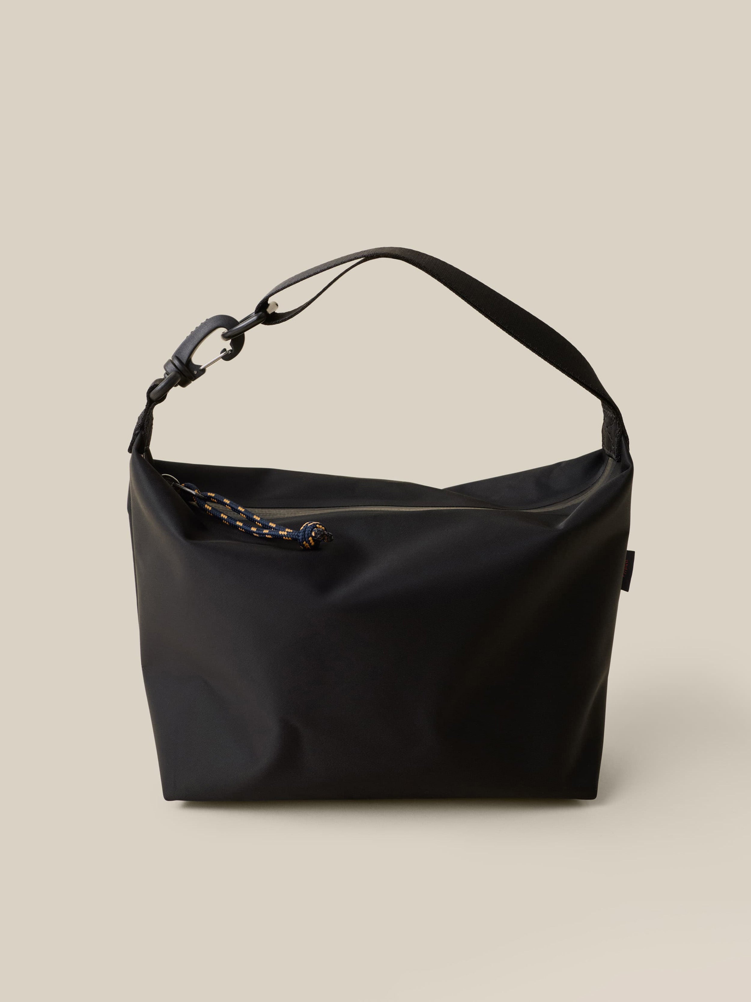 Black dry bag with a strap against a beige background