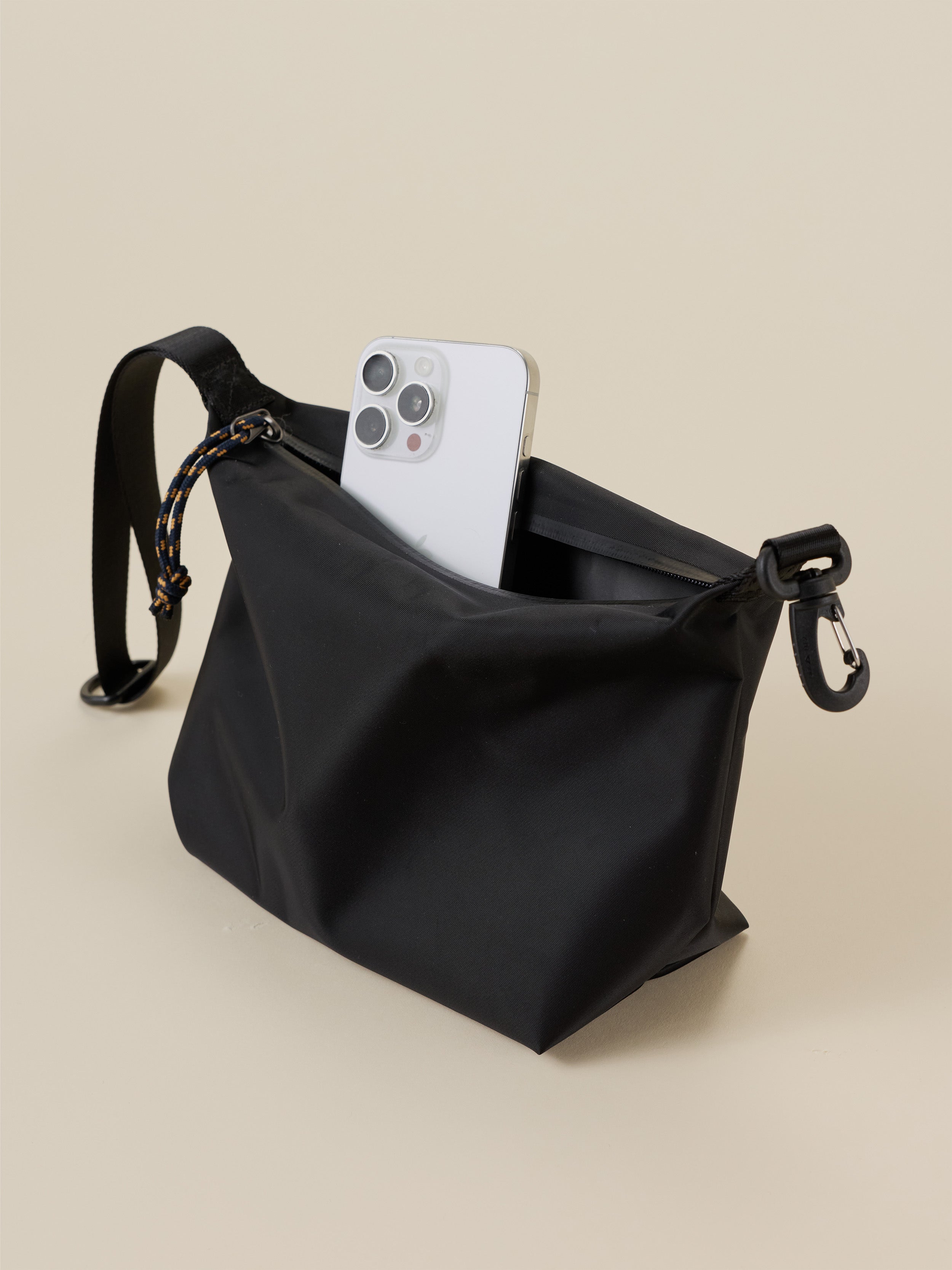 Black dry bag with a phone inside on a beige background