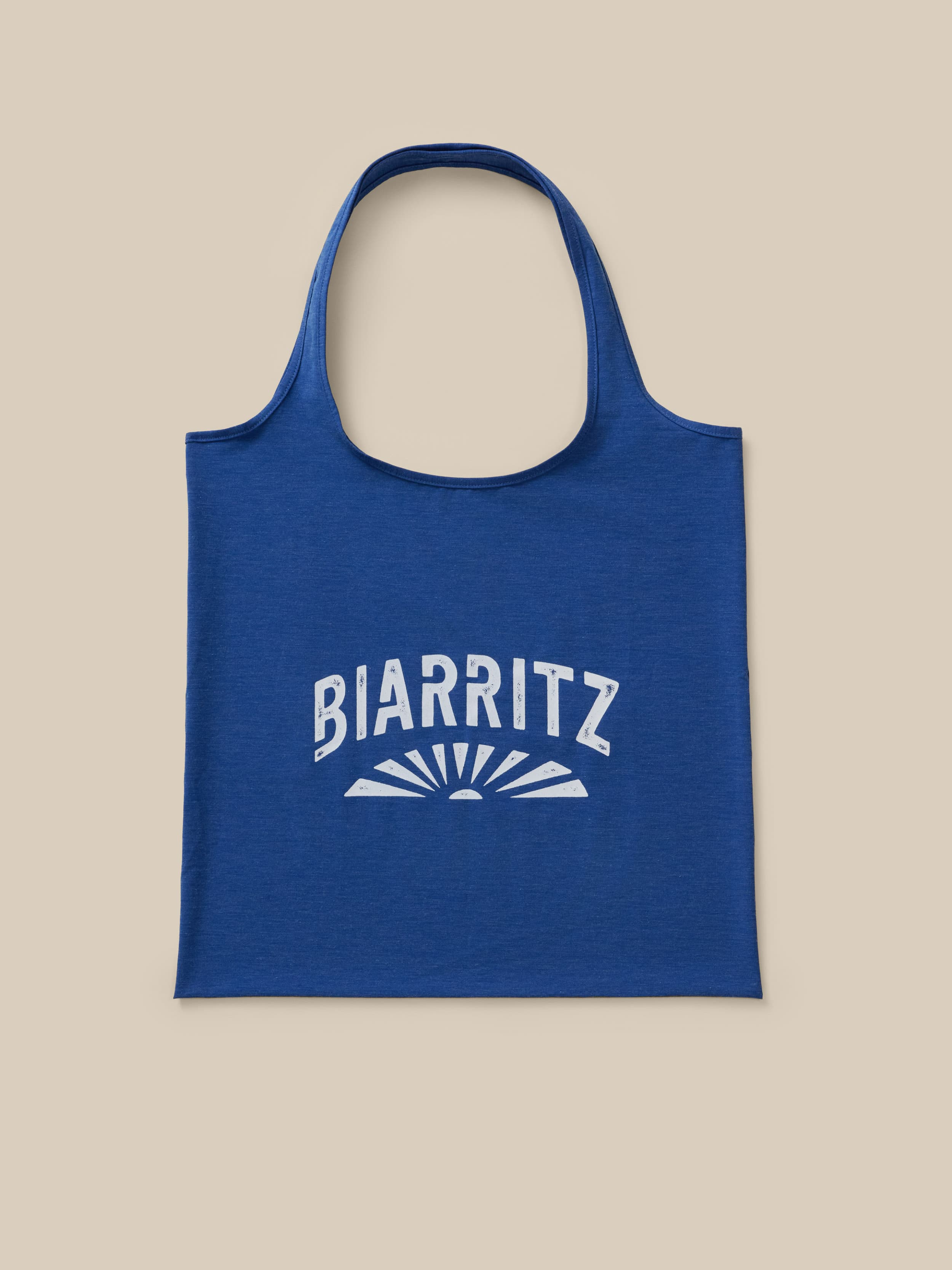 Blue tote bag with "Biarritz" graphic logo on the front against a neutral background
