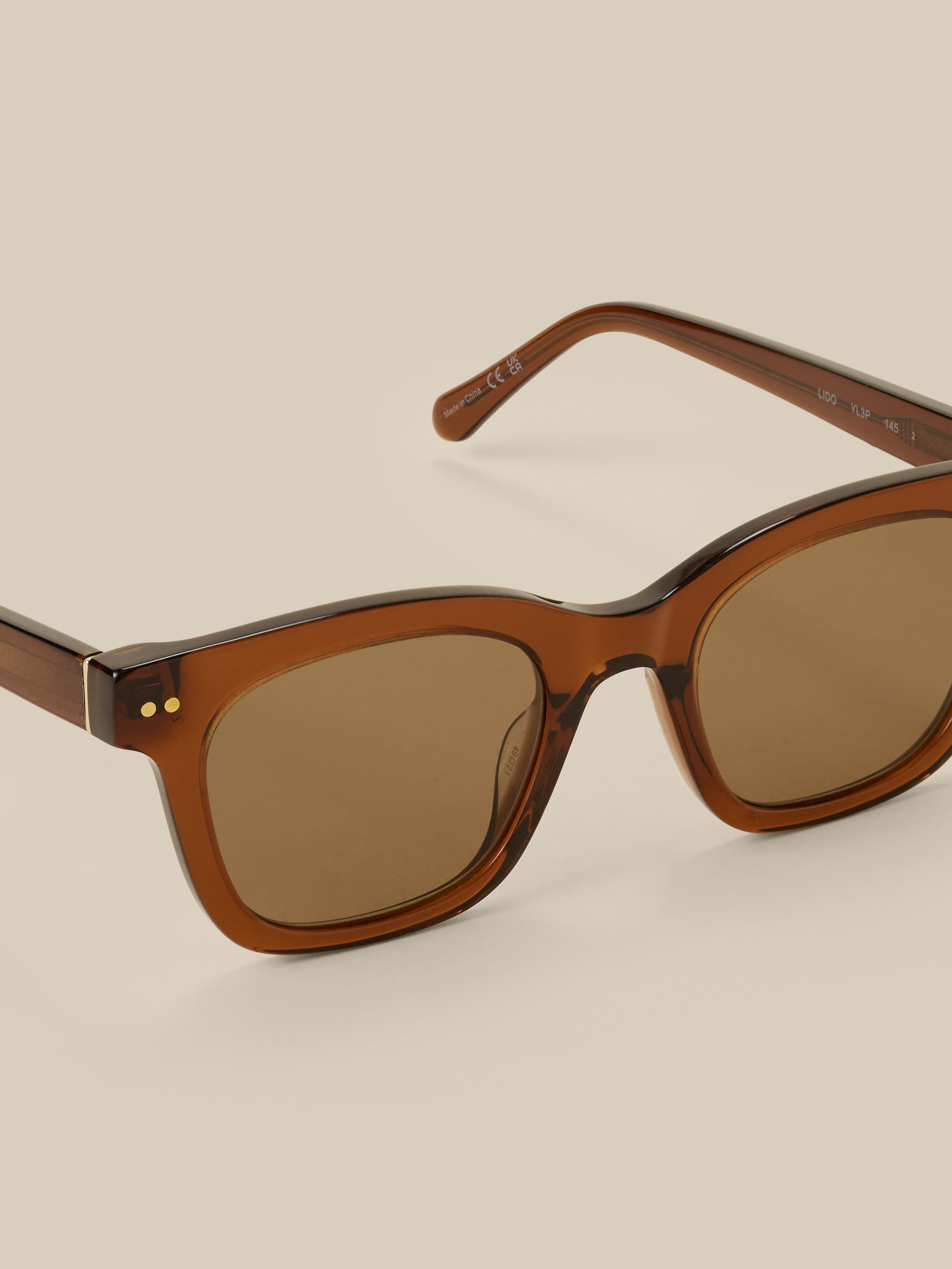 Brown sunglasses against a beige background