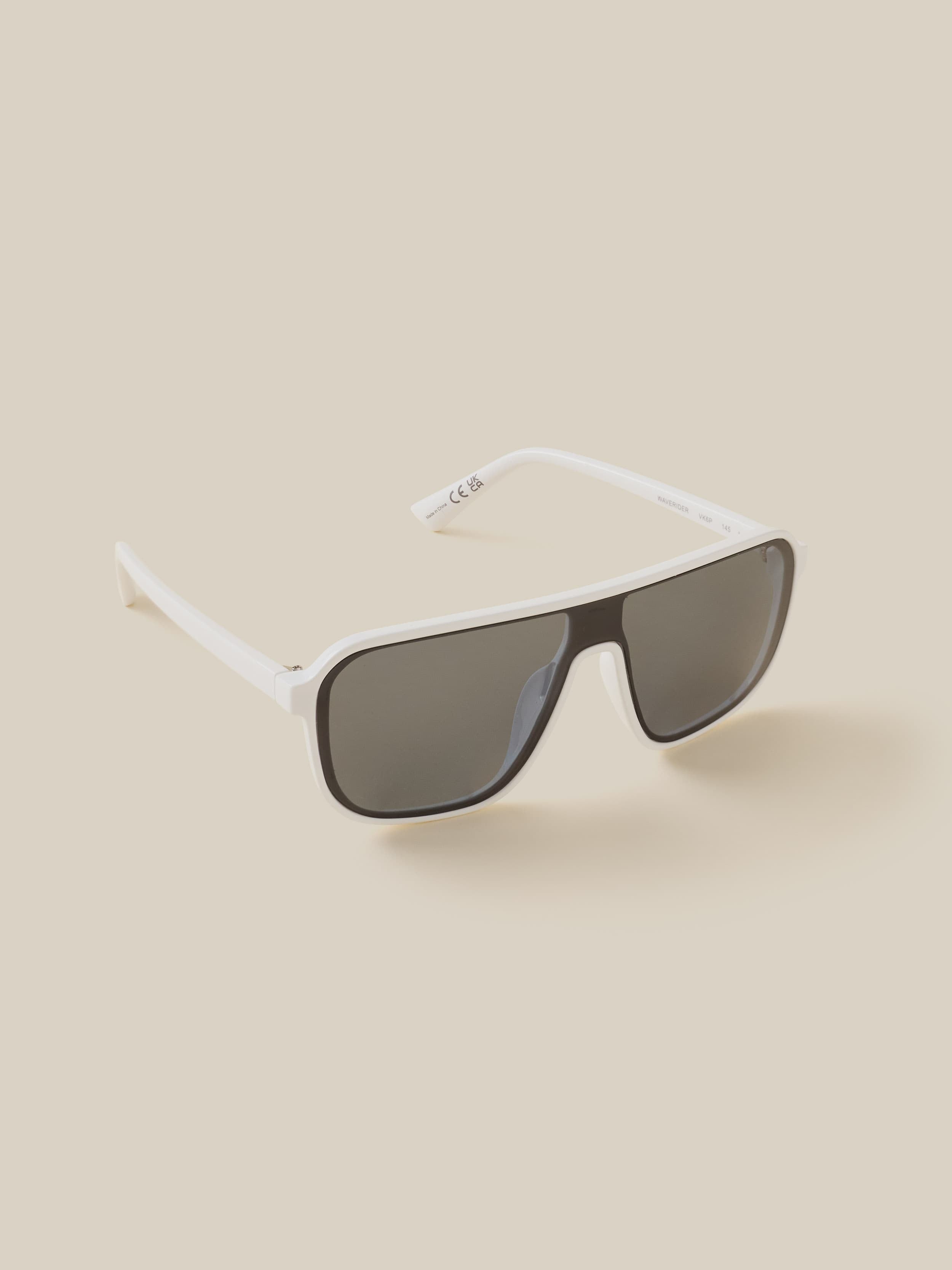 Sunglasses with a white frame and dark lenses on a beige background