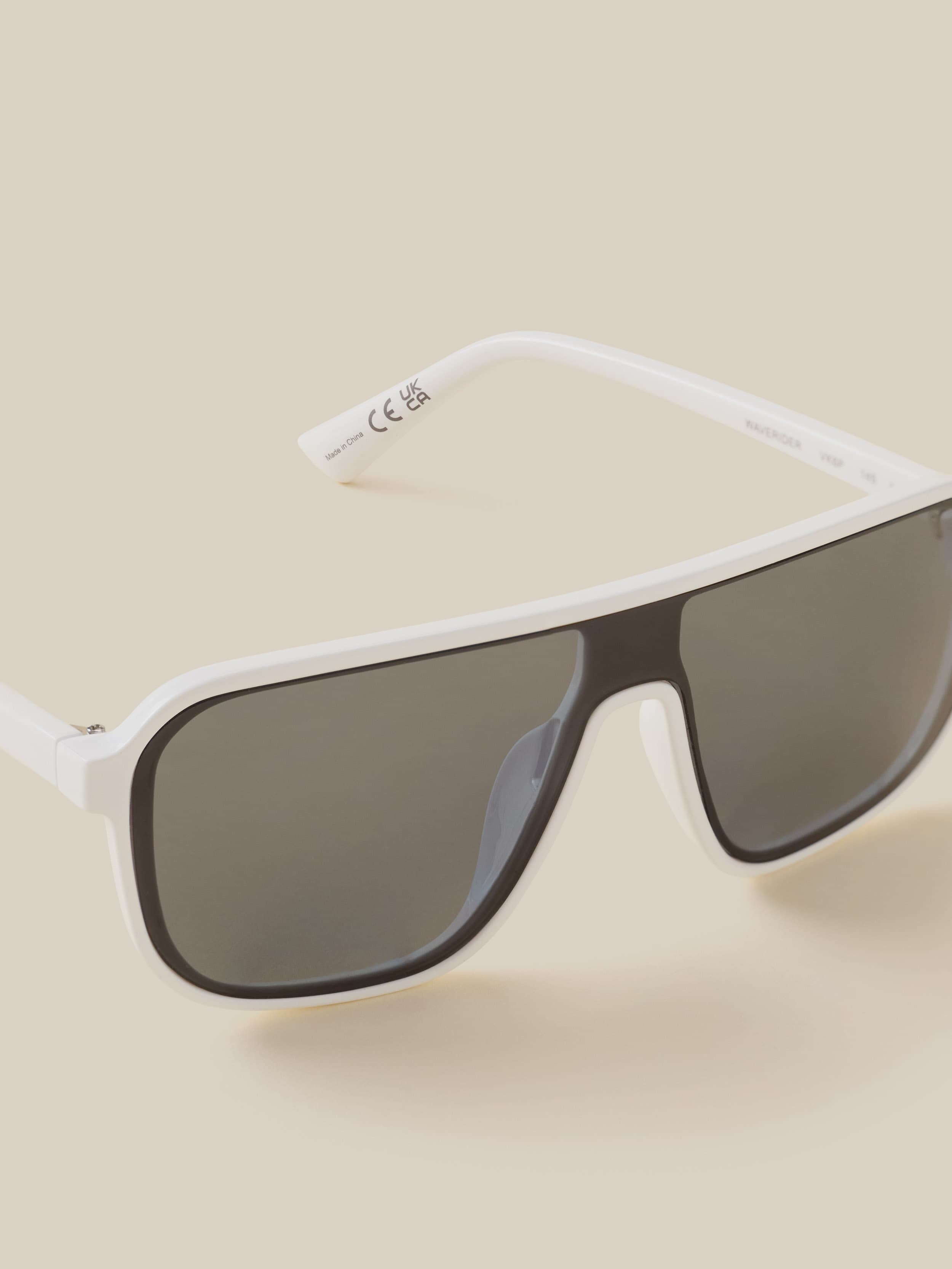 Sunglasses with white frame and dark lenses on a beige background