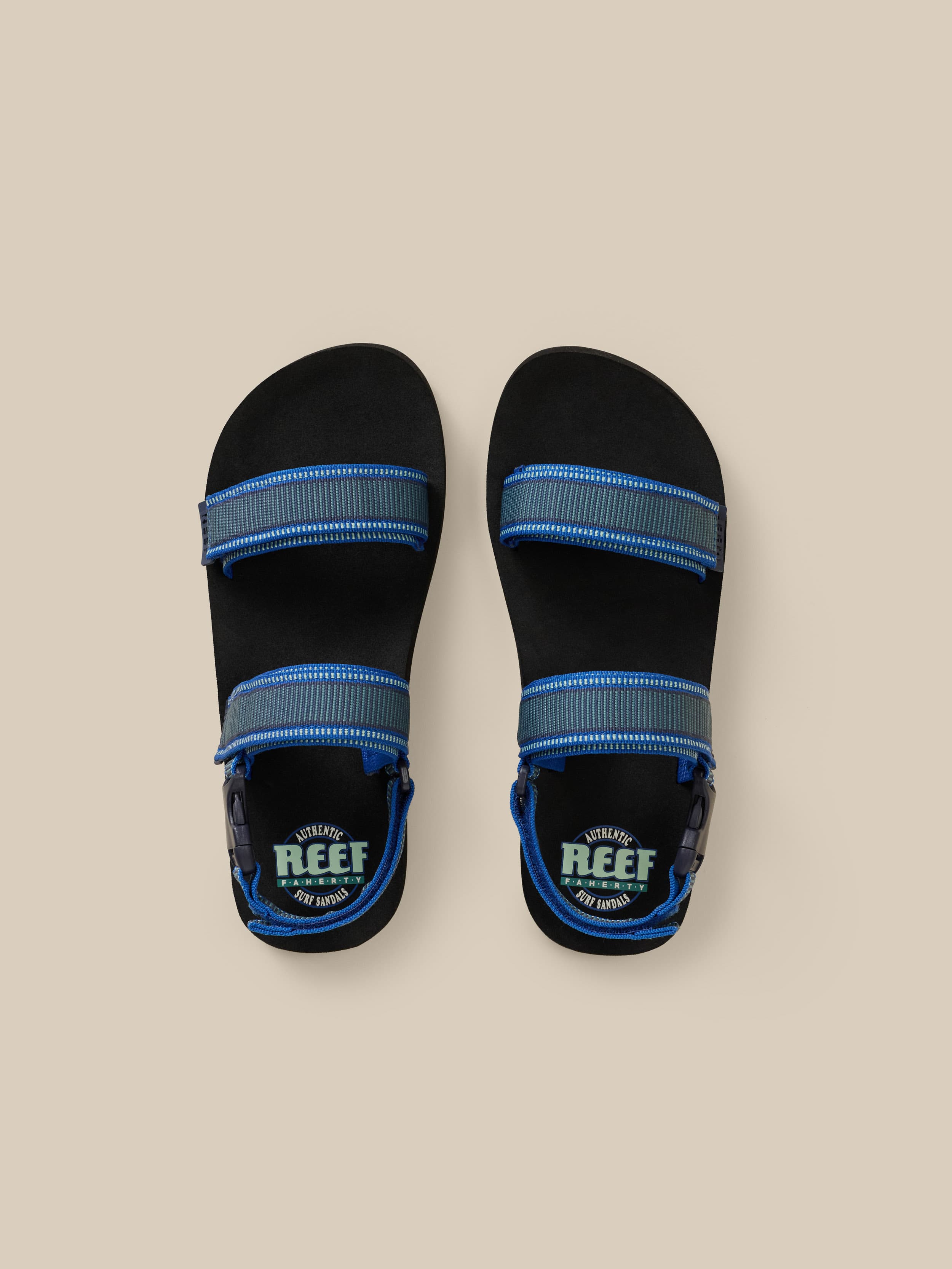 Black sandals with blue straps on a beige background