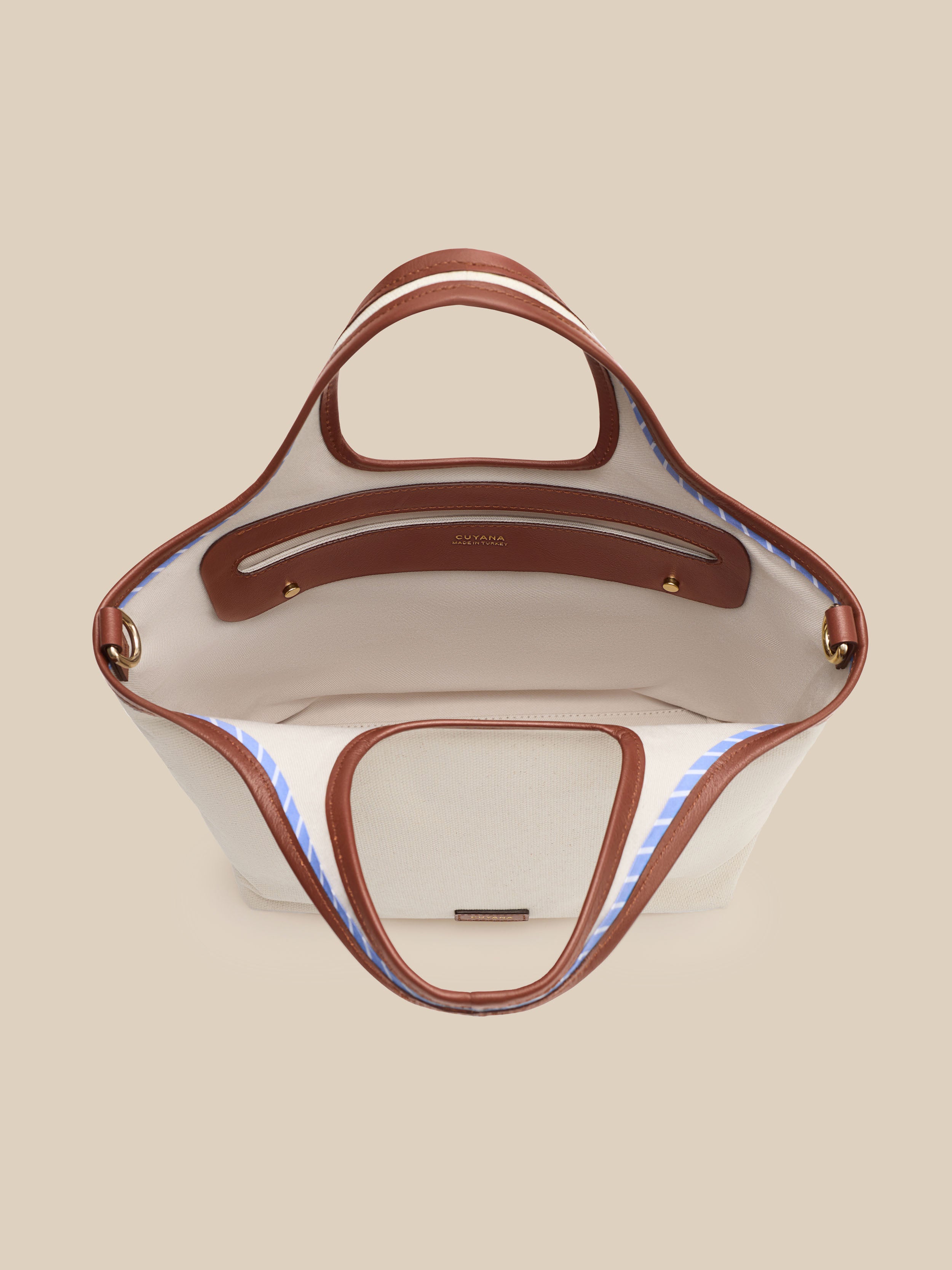 Beige canvas handbag with a beige interior on a beige background