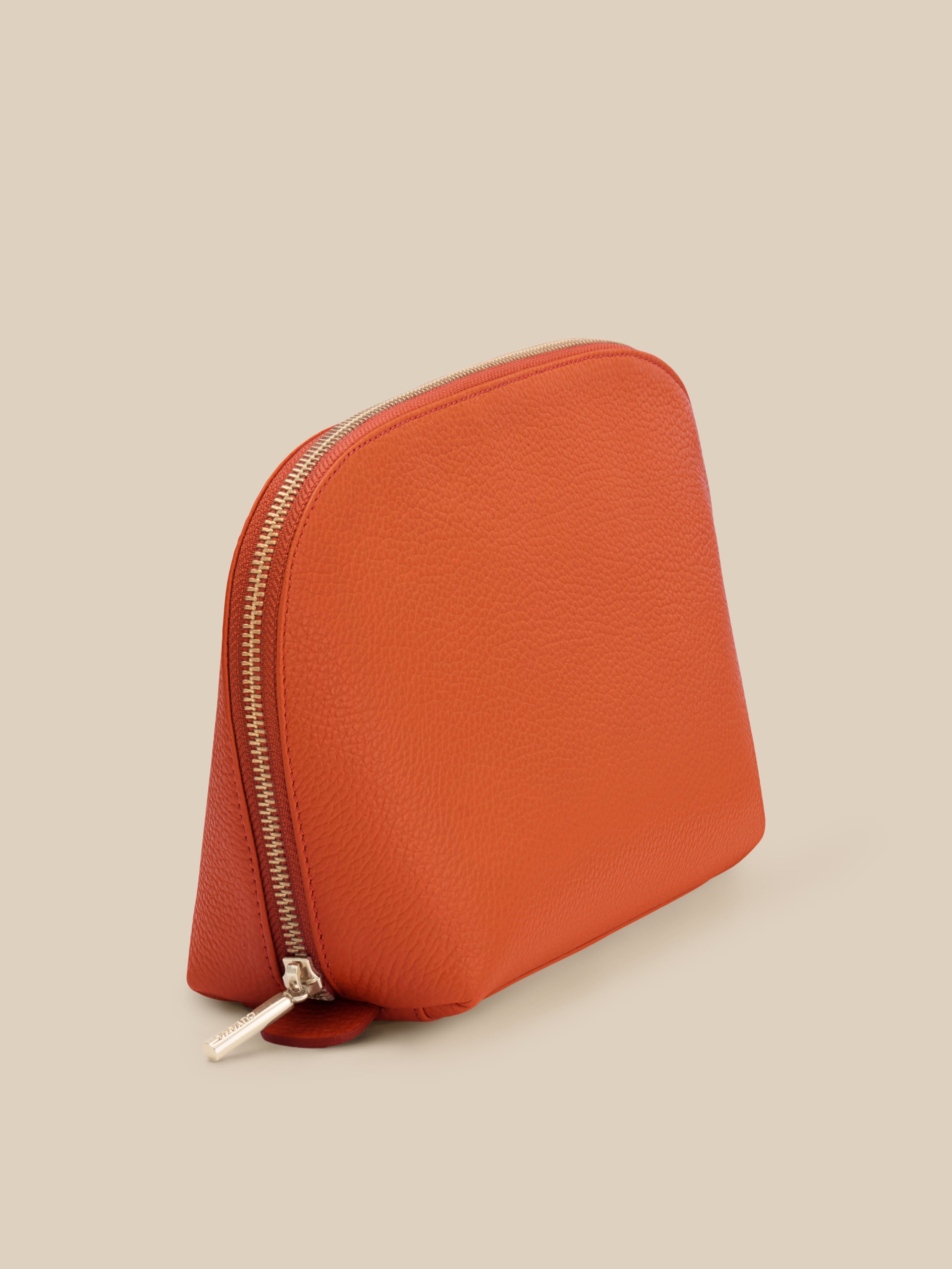 Small orange cosmetic pouch against a beige background