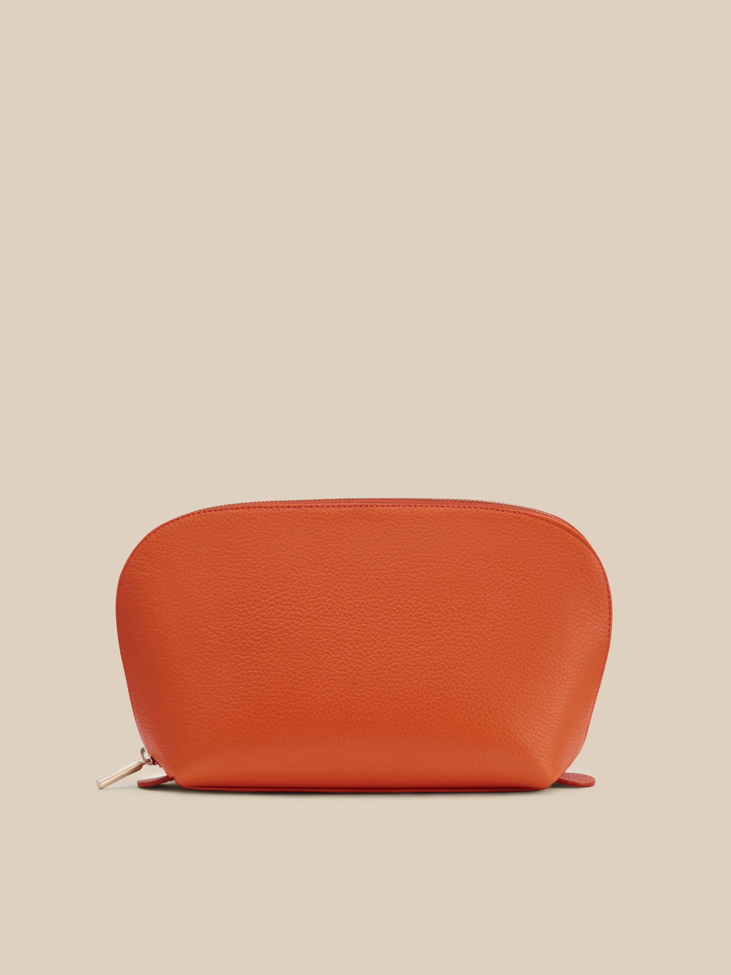 Small orange cosmetic pouch against a beige background