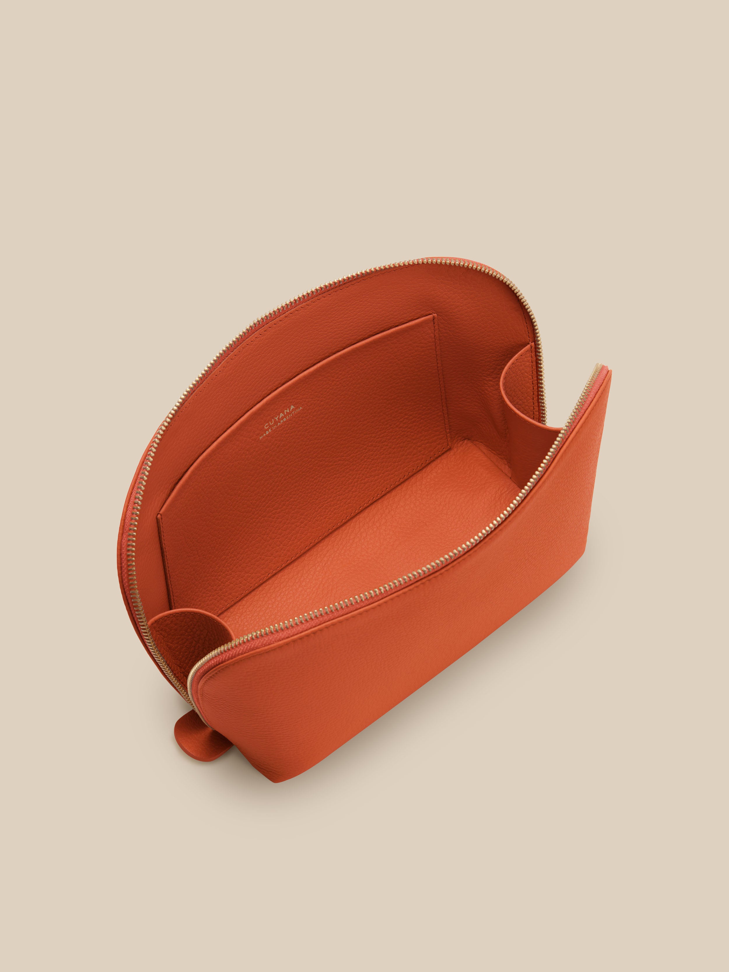 Small orange cosmetic pouch against a beige background