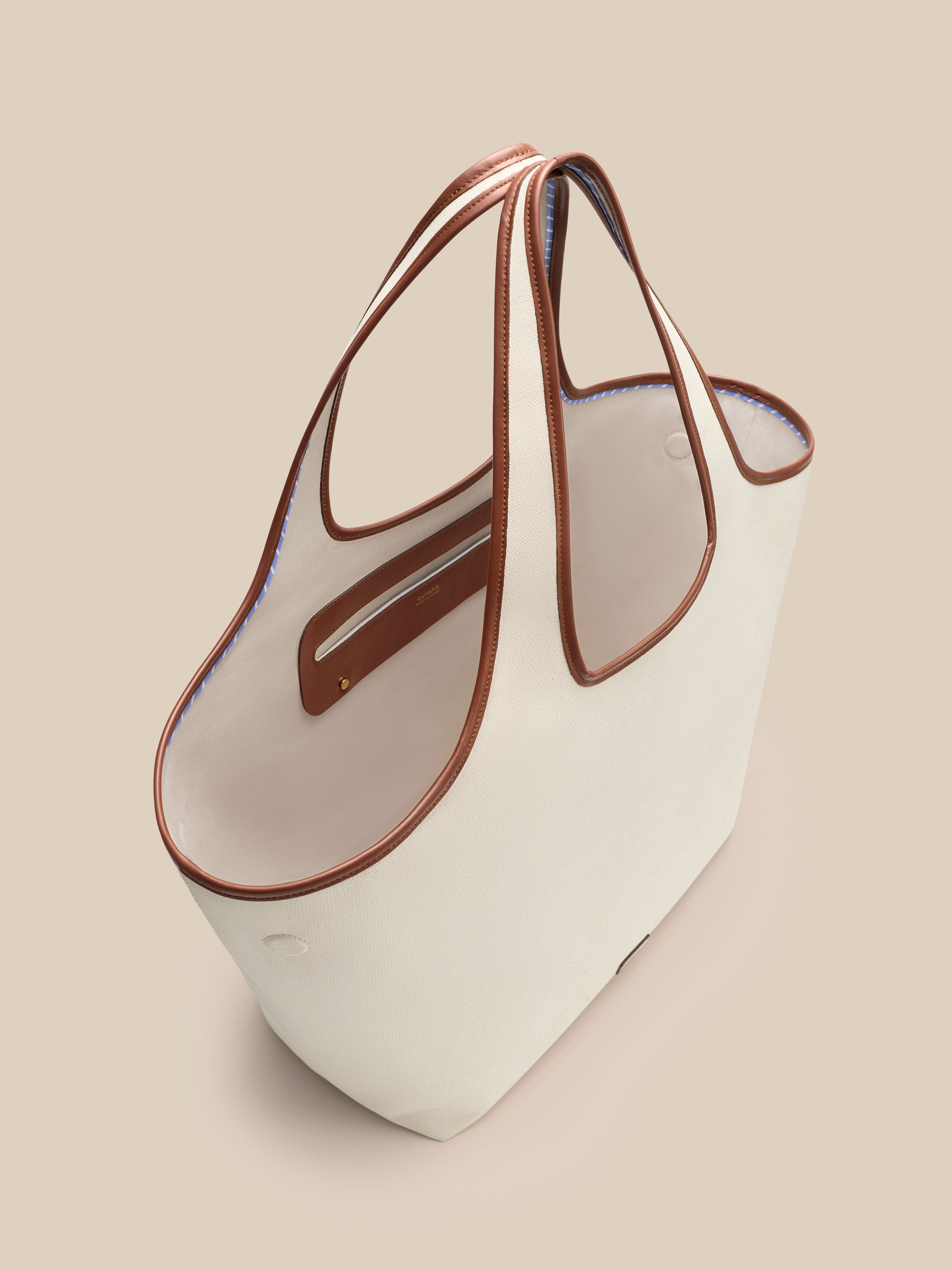 Beige canvas handbag with a beige interior on a beige background