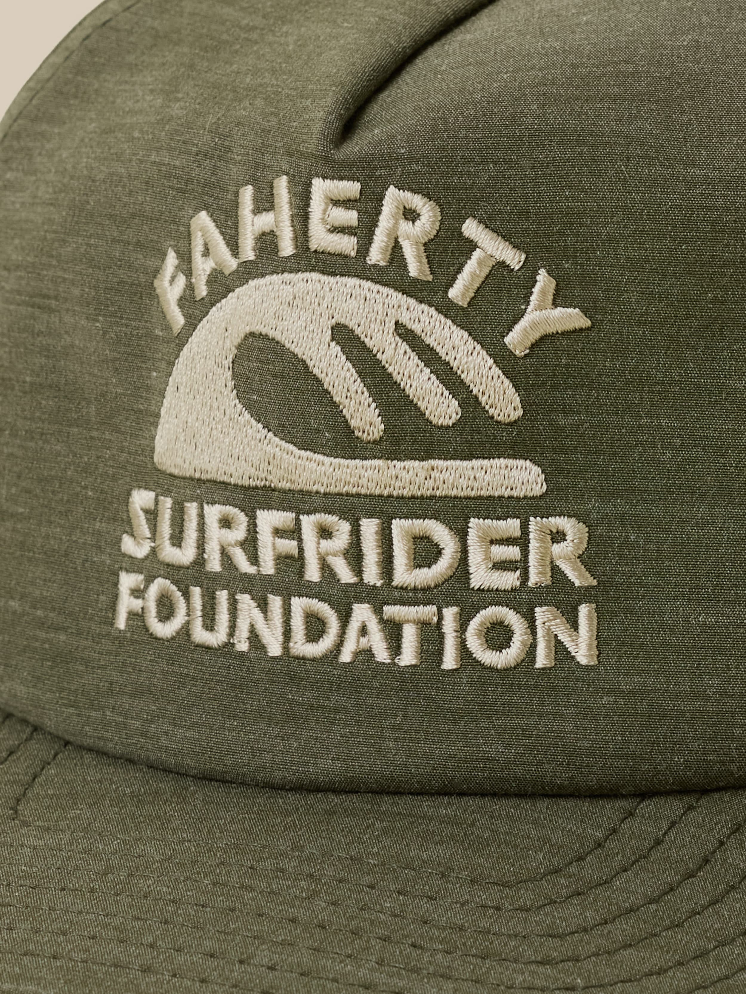 Green cap with 'Faherty x Surfrider Foundation' logo on a beige background