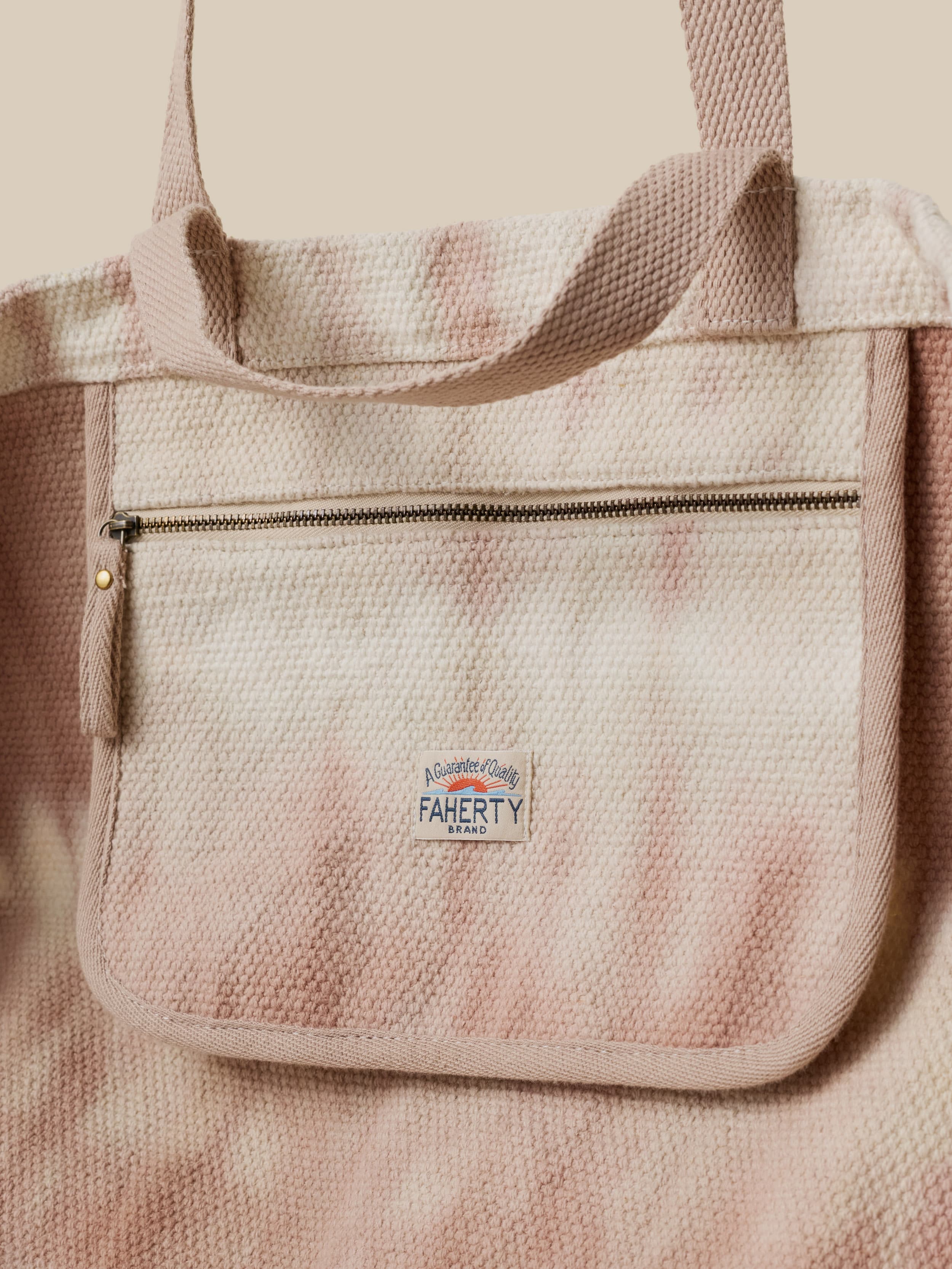 Textured canvas tie dye beach bag with a visible Faherty brand logo on a beige background