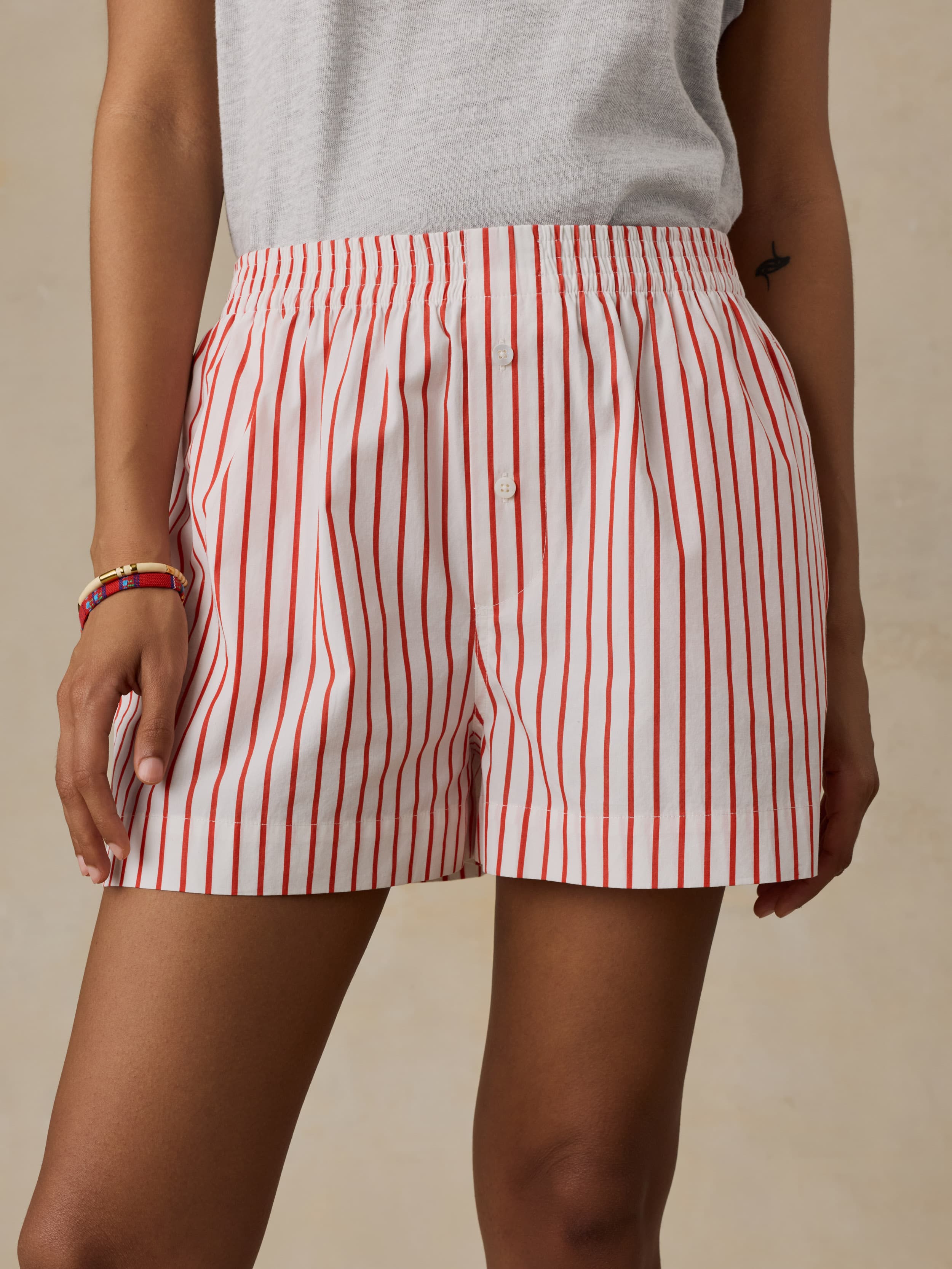 Woman wearing red and white striped boxer shorts against a beige background