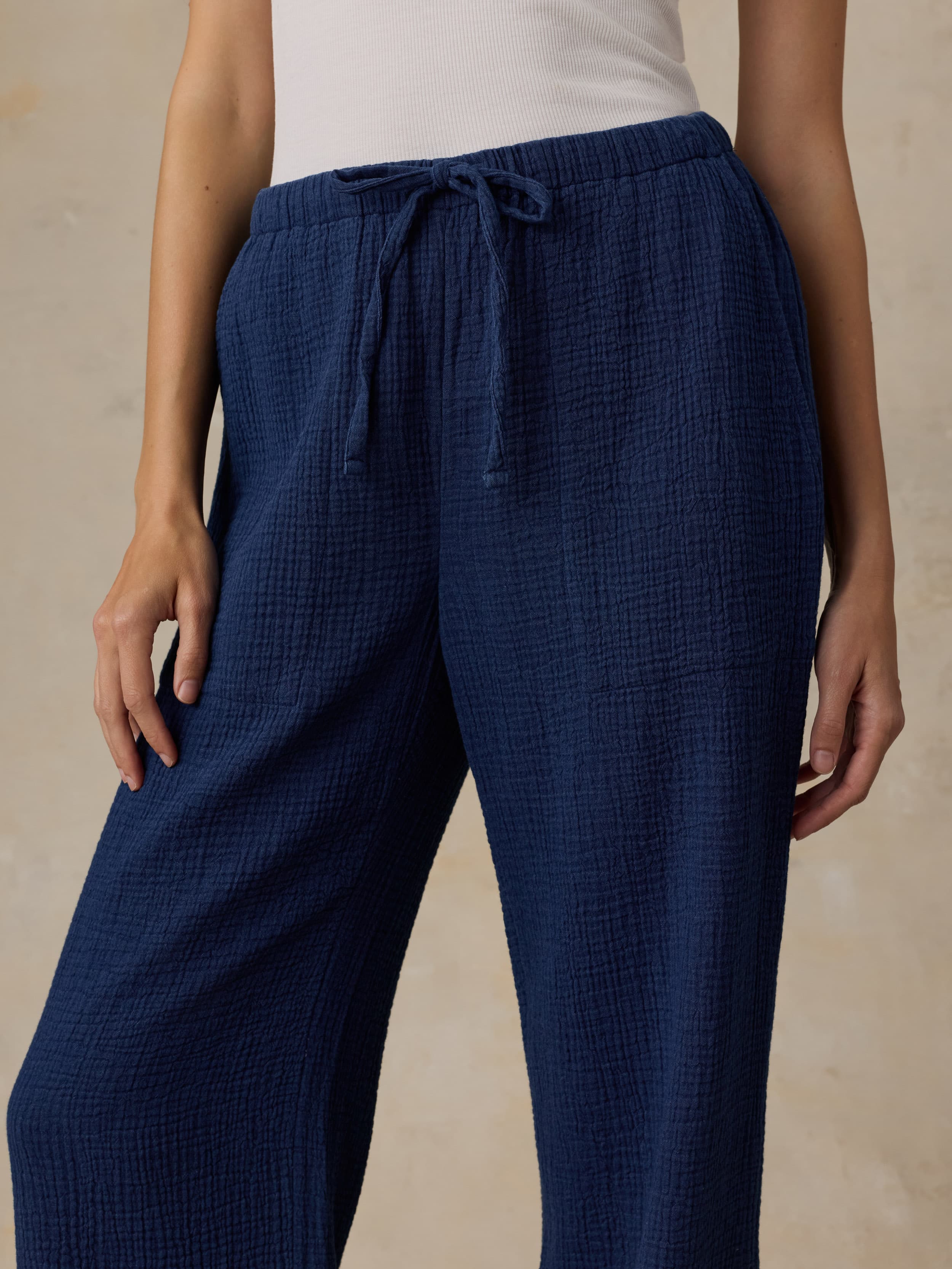 Navy blue pants worn by a woman on a beige background