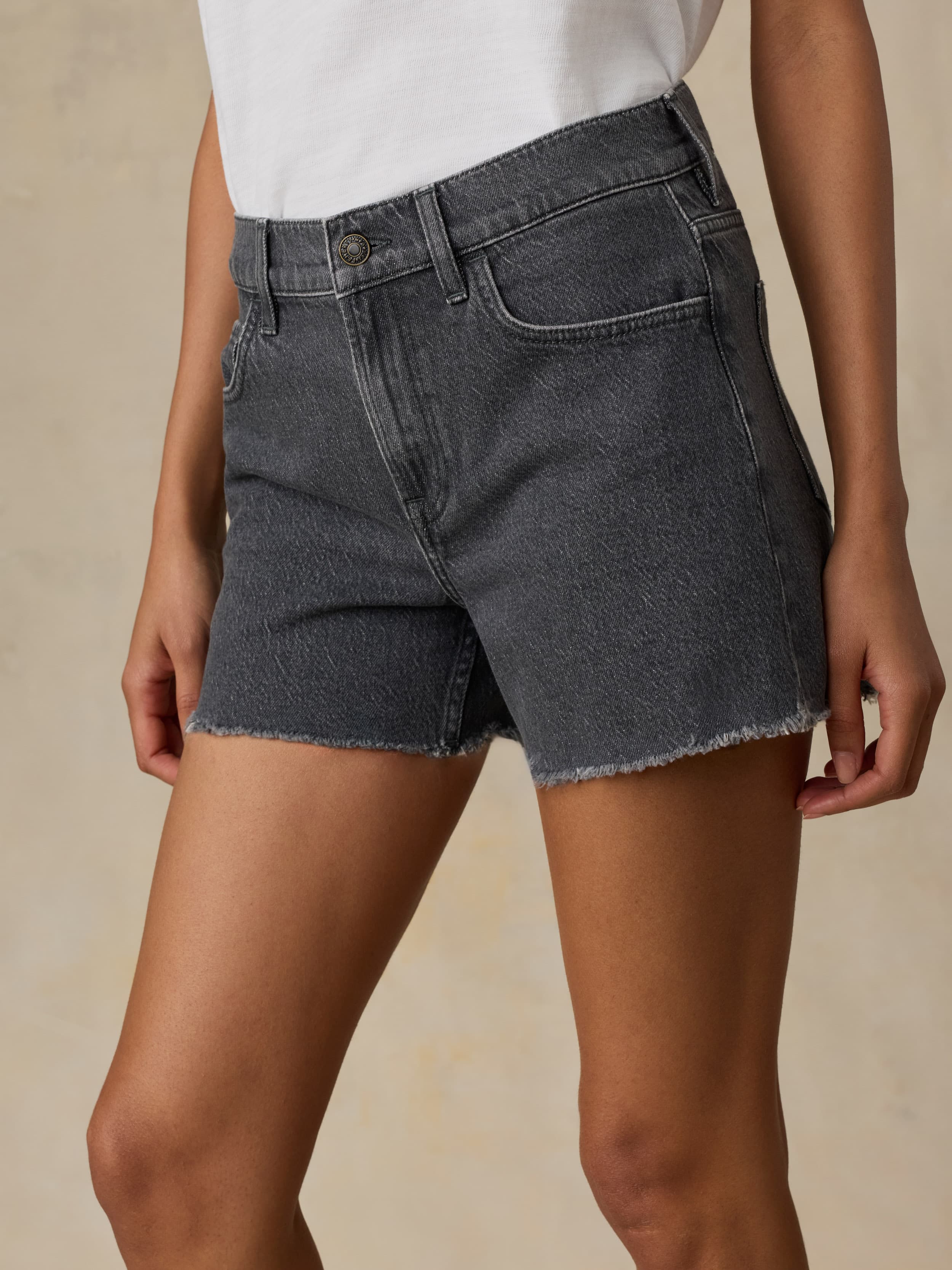 Woman wearing black denim shorts on a beige background