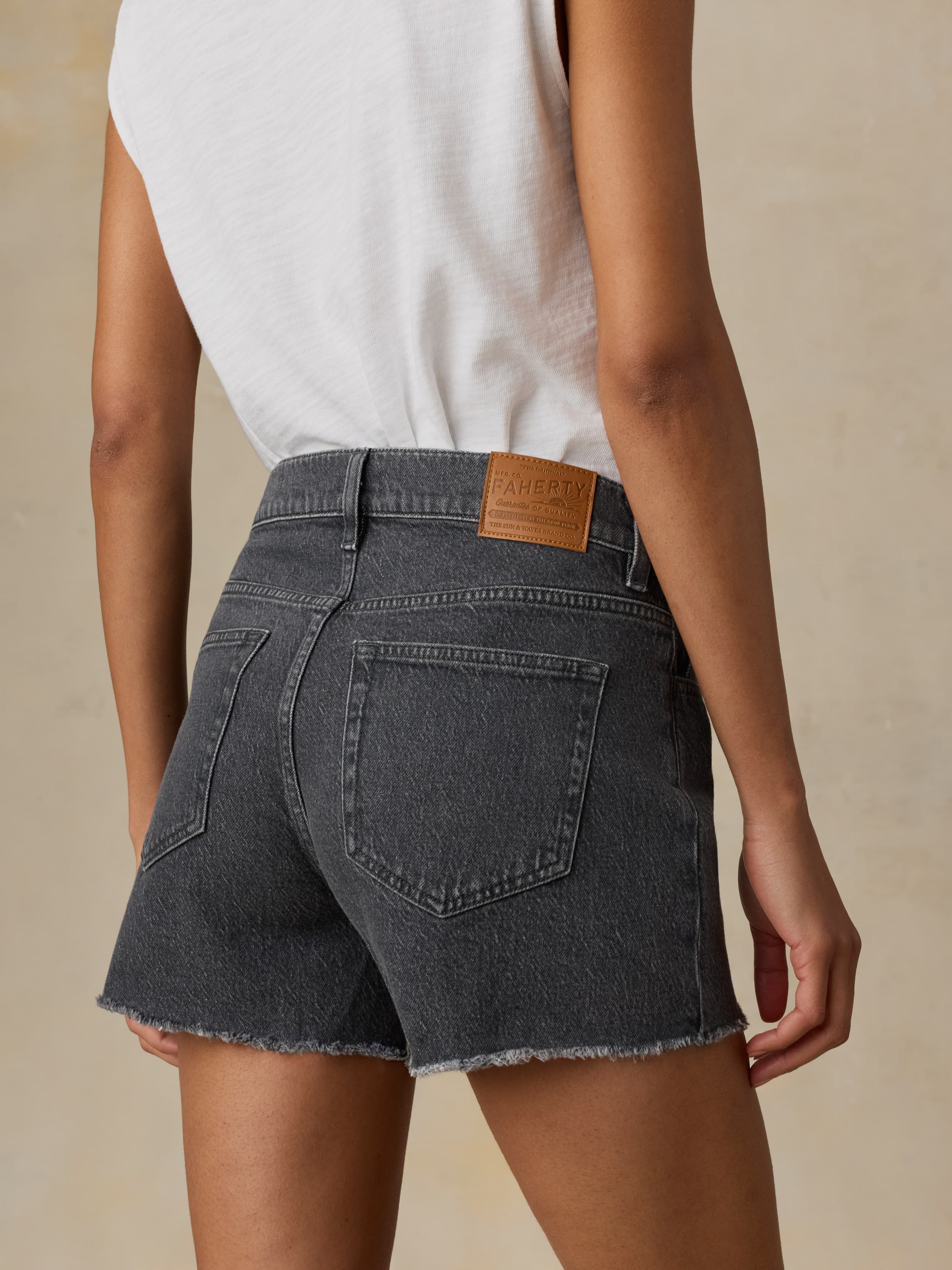 Woman wearing a black denim skirt with a visible brand patch on a beige background