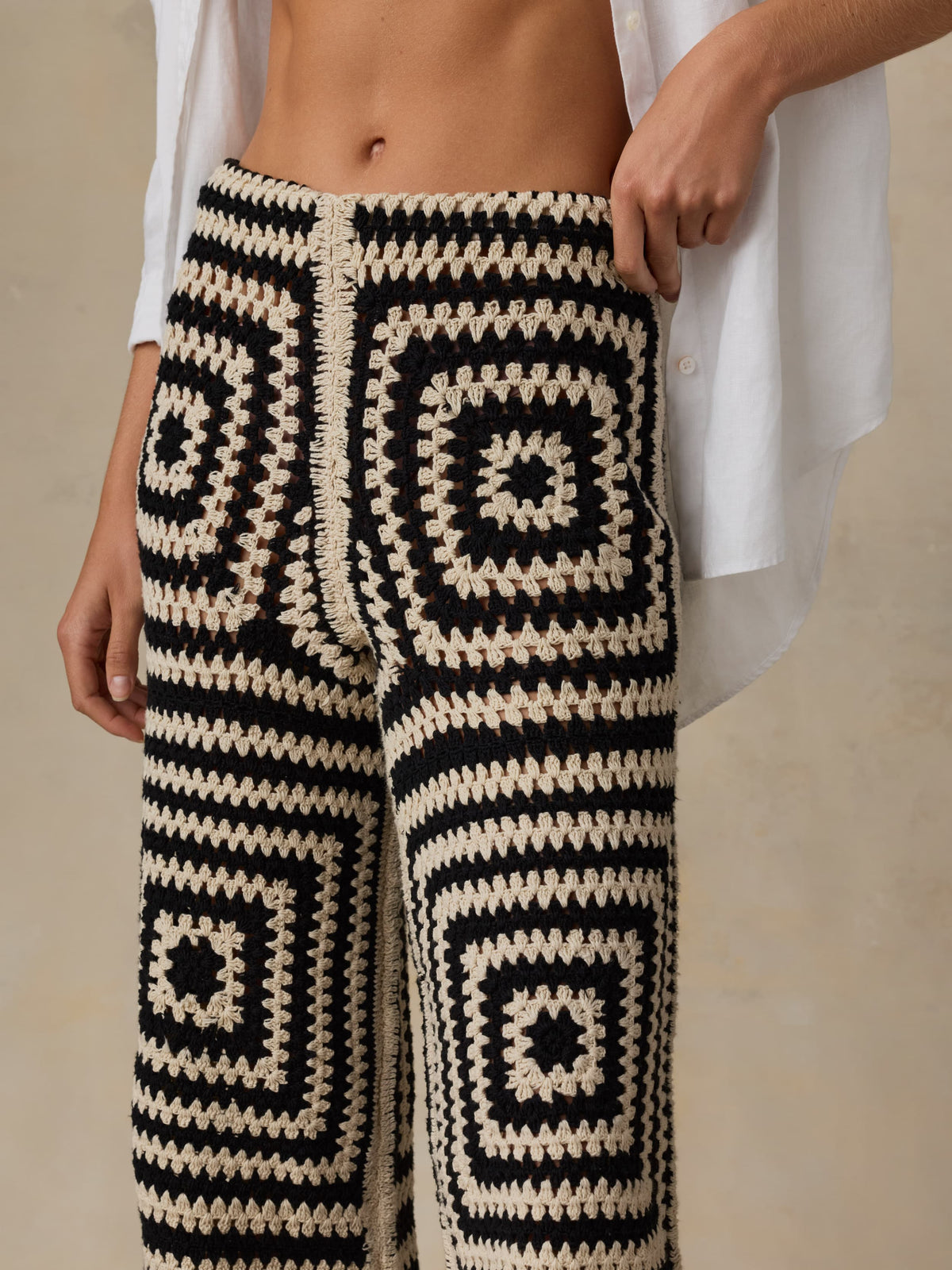 Person wearing black and white patterned pants with a neutral background, image 2 of 5