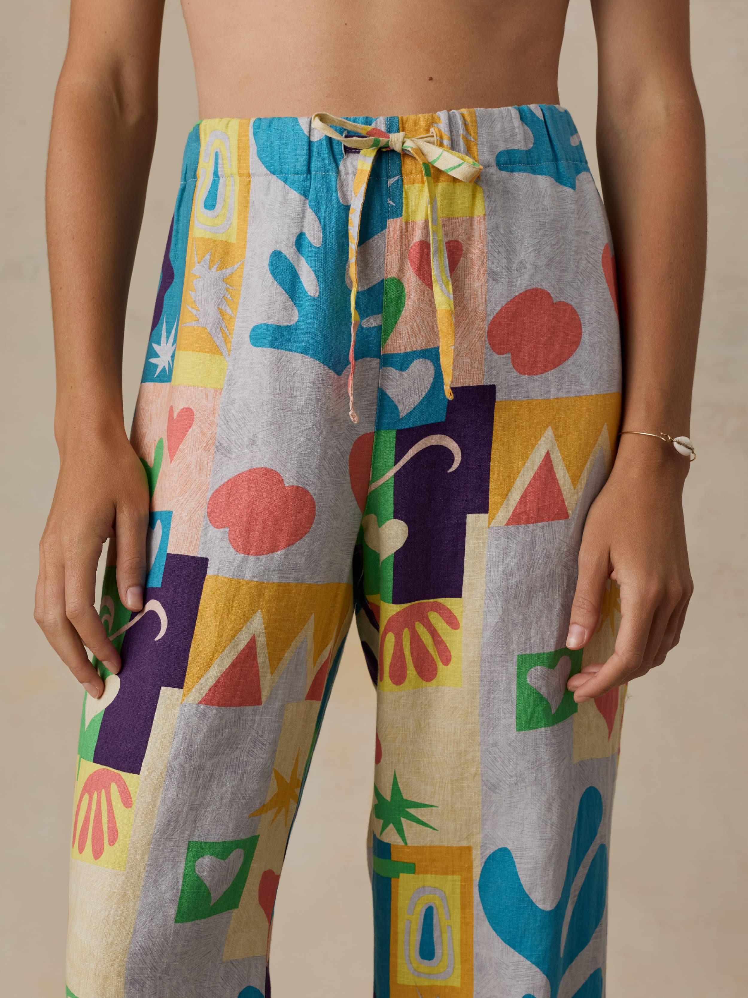 Colorful geometric-patterned pants worn by a woman on a beige background