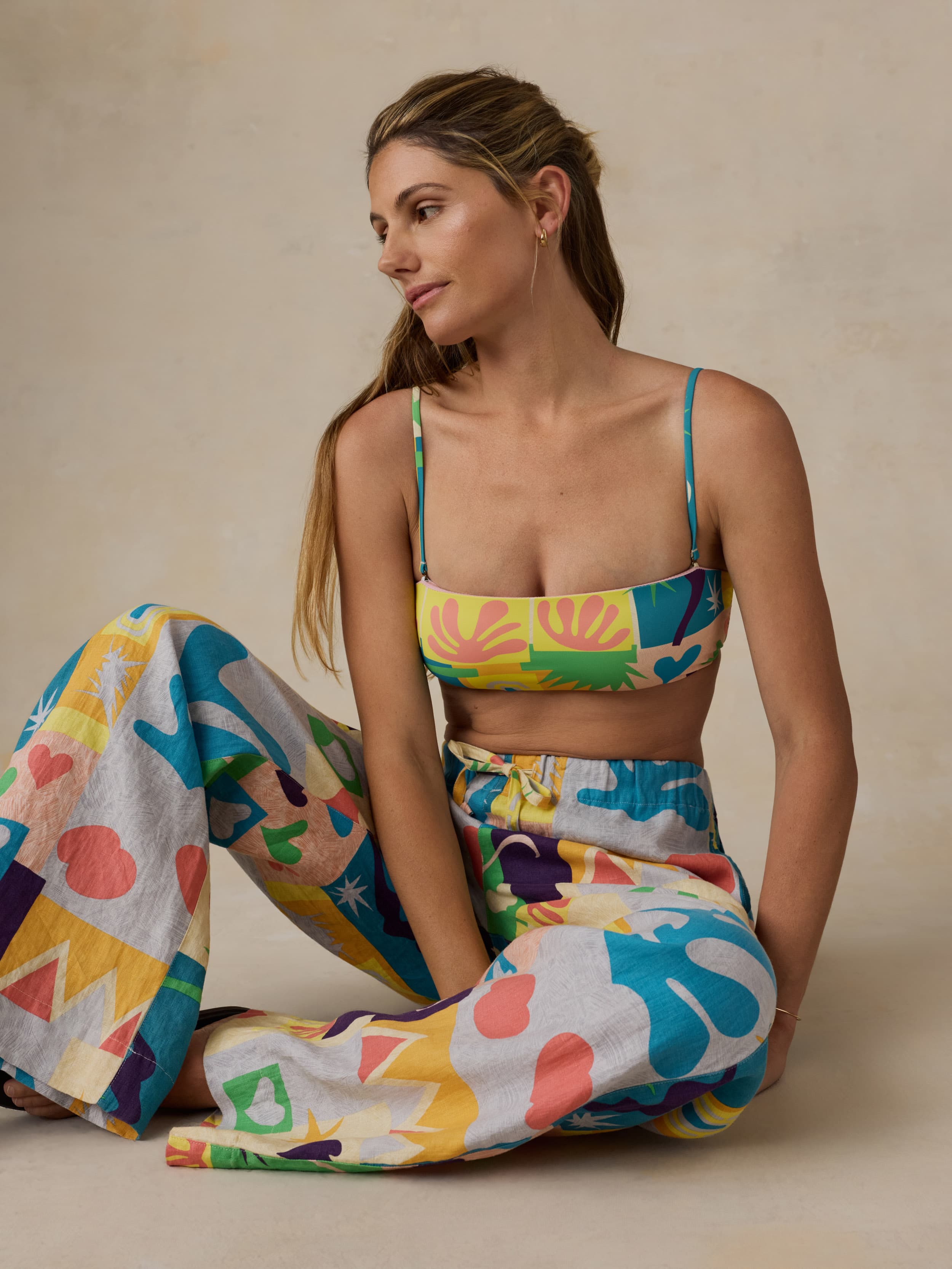 Woman wearing a colorful bikini top with matching pants on a beige background