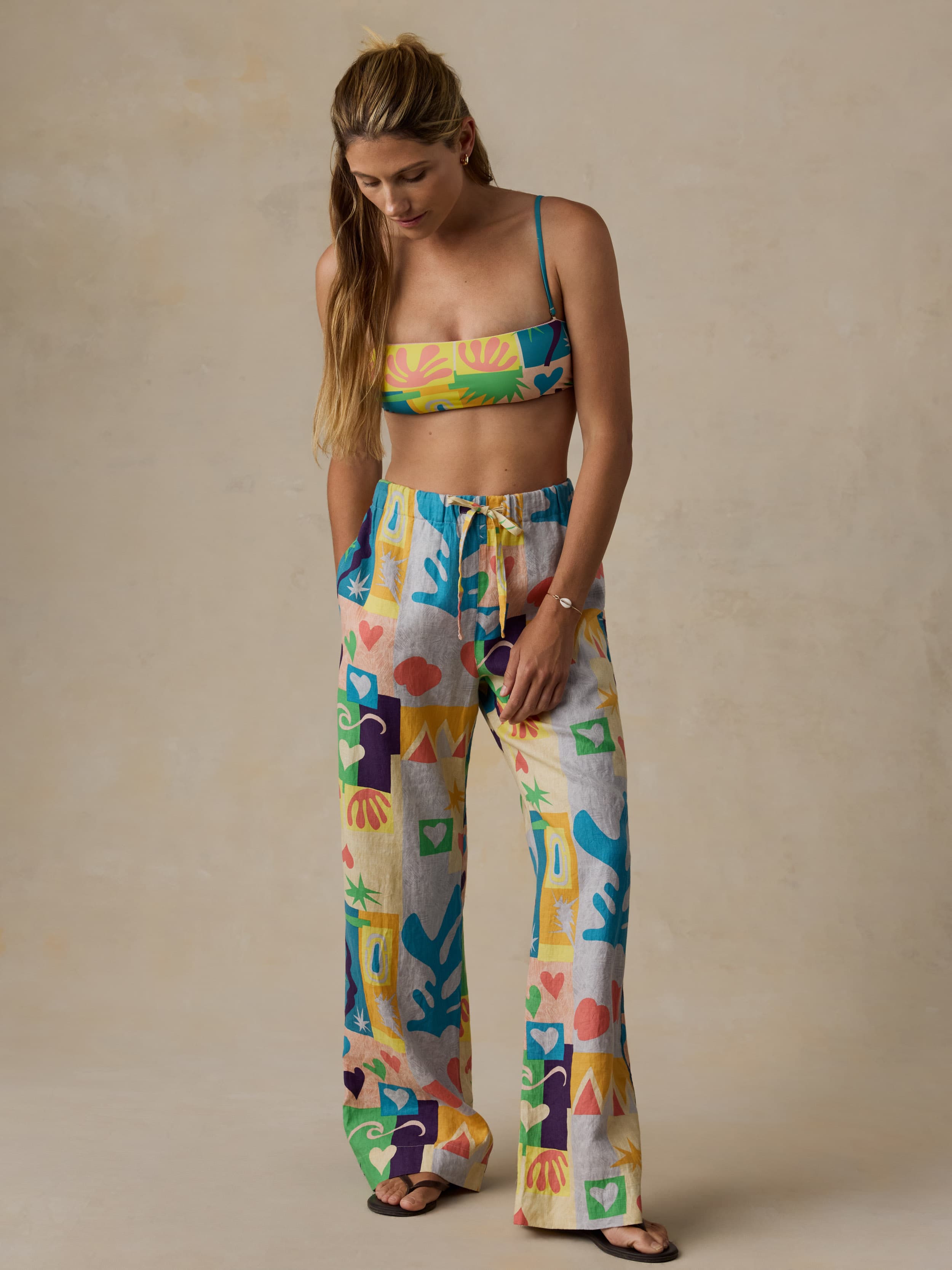 Woman wearing a colorful patterned top and pants on a beige background
