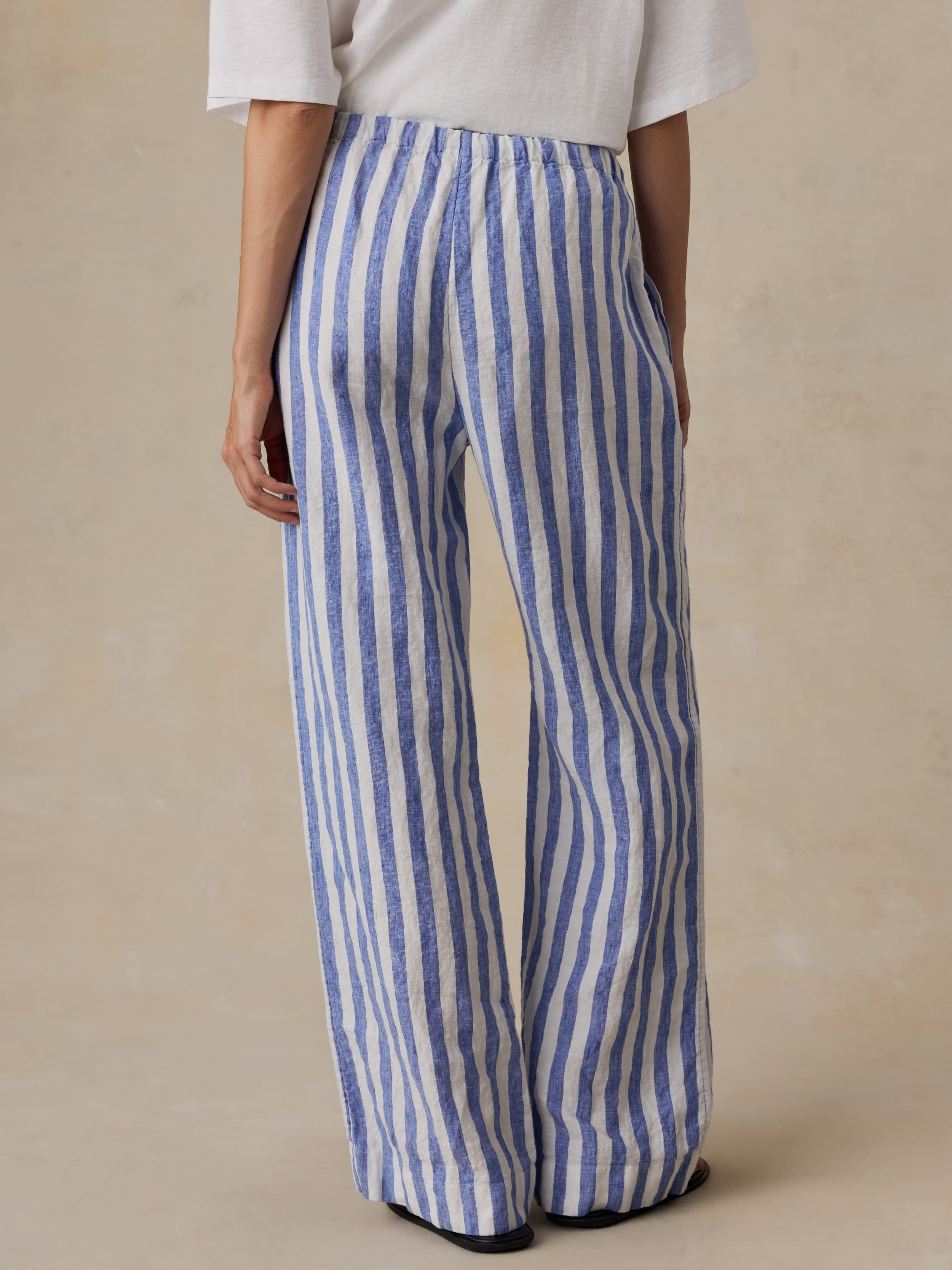 Woman wearing blue and white striped pants on a beige background