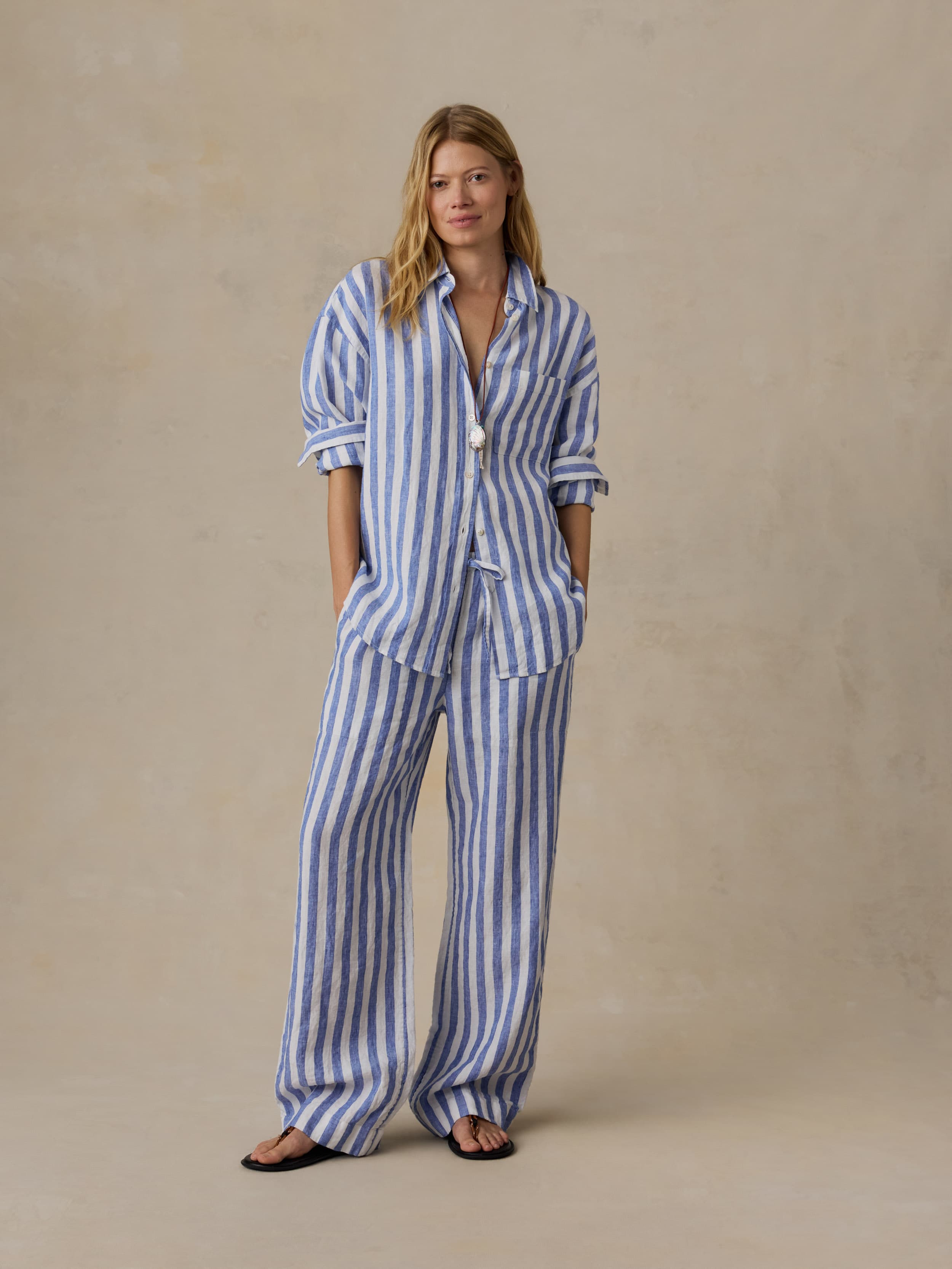 Woman wearing a blue and white striped set against a beige background