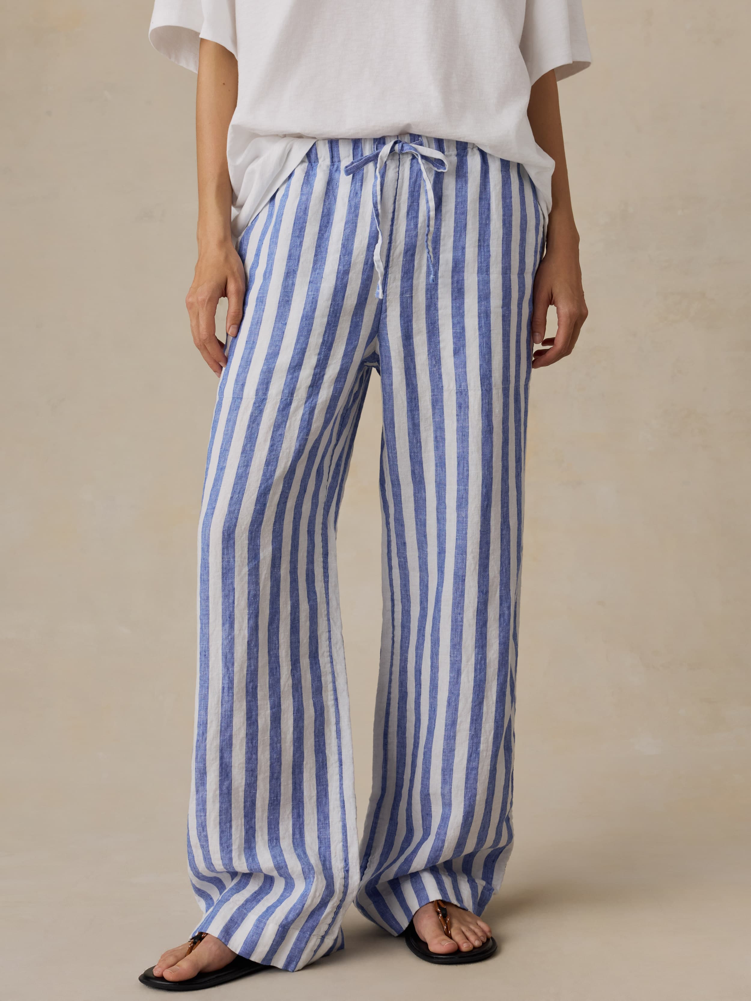 Woman wearing blue and white striped pants on a beige background