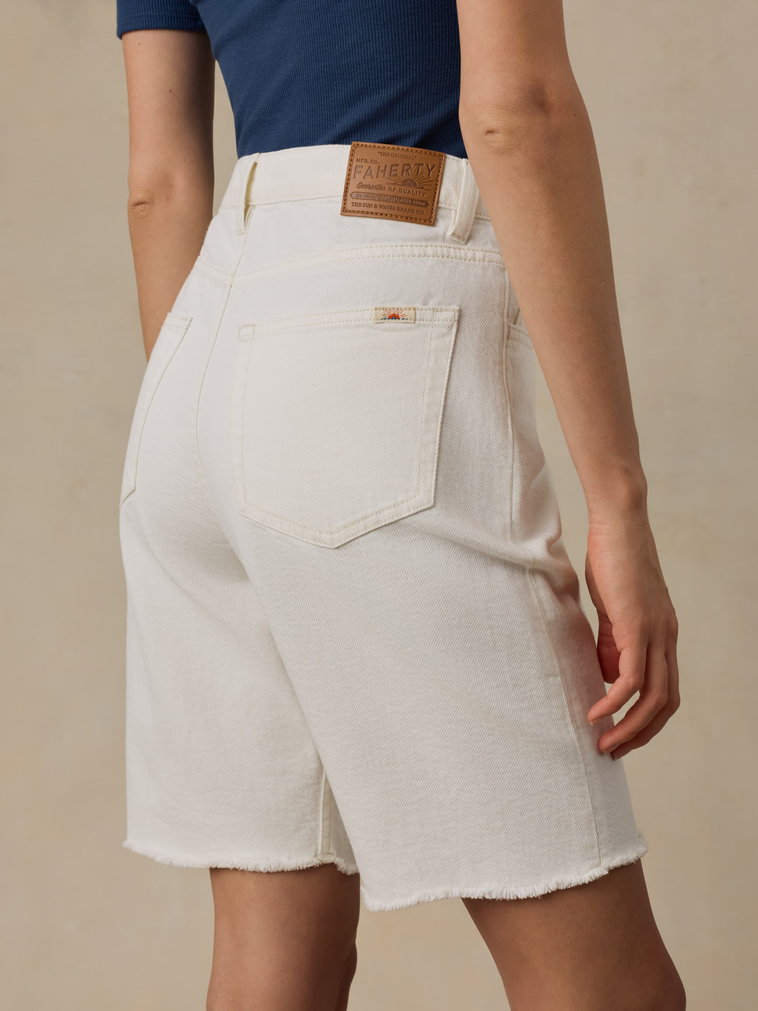 Woman wearing white denim shorts against a beige background