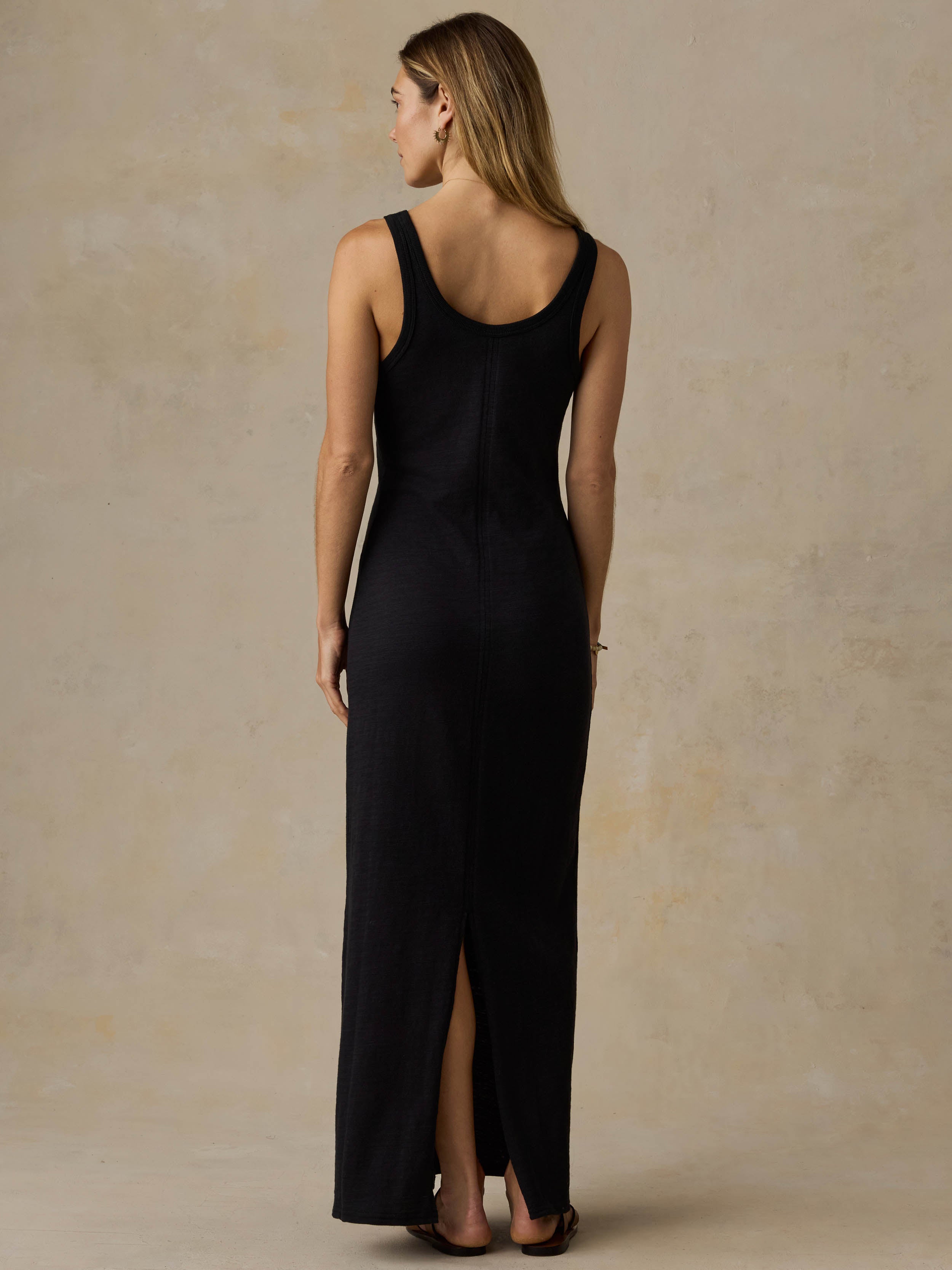 Woman wearing a black sleeveless maxi dress against a beige background