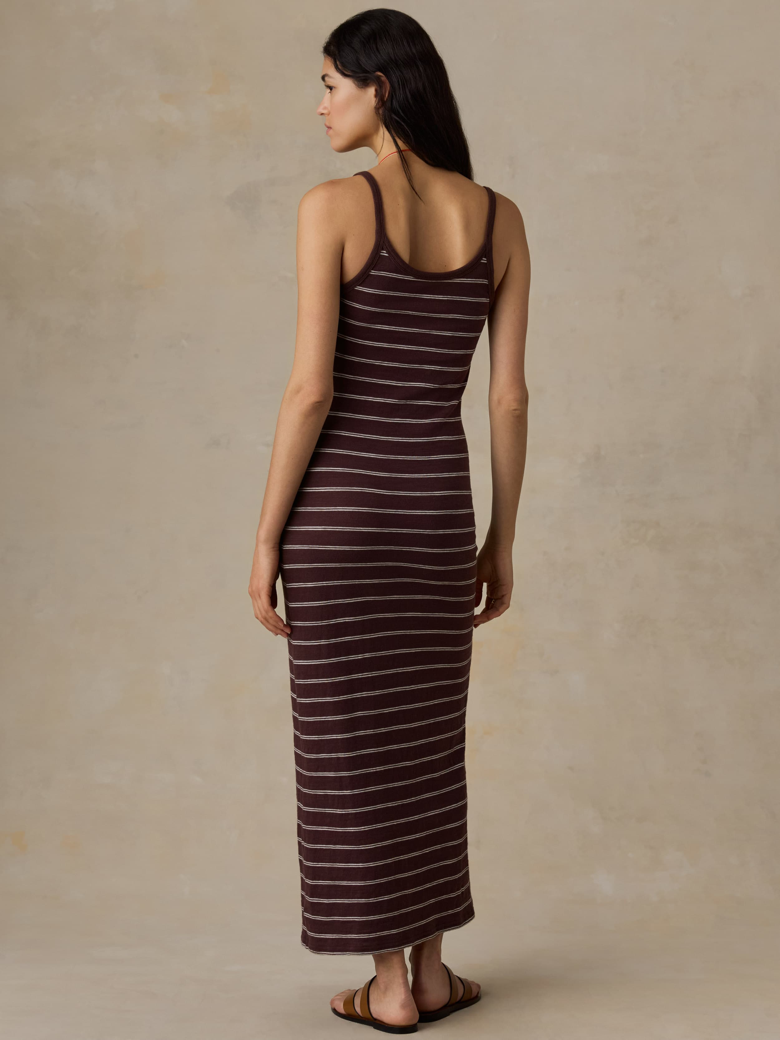 Woman wearing a brown striped tank dress against a beige background