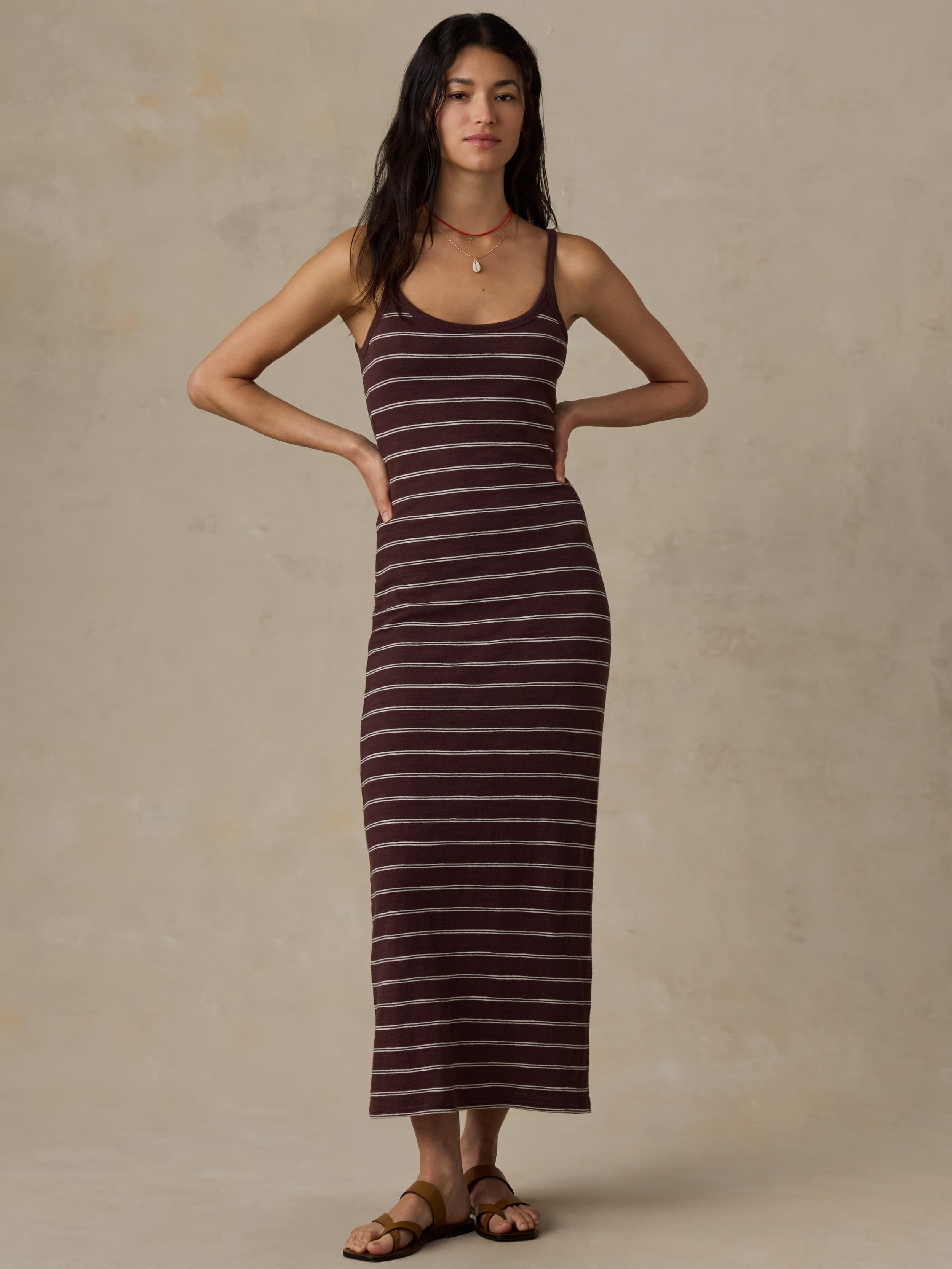 Woman wearing a brown striped tank dress against a beige background