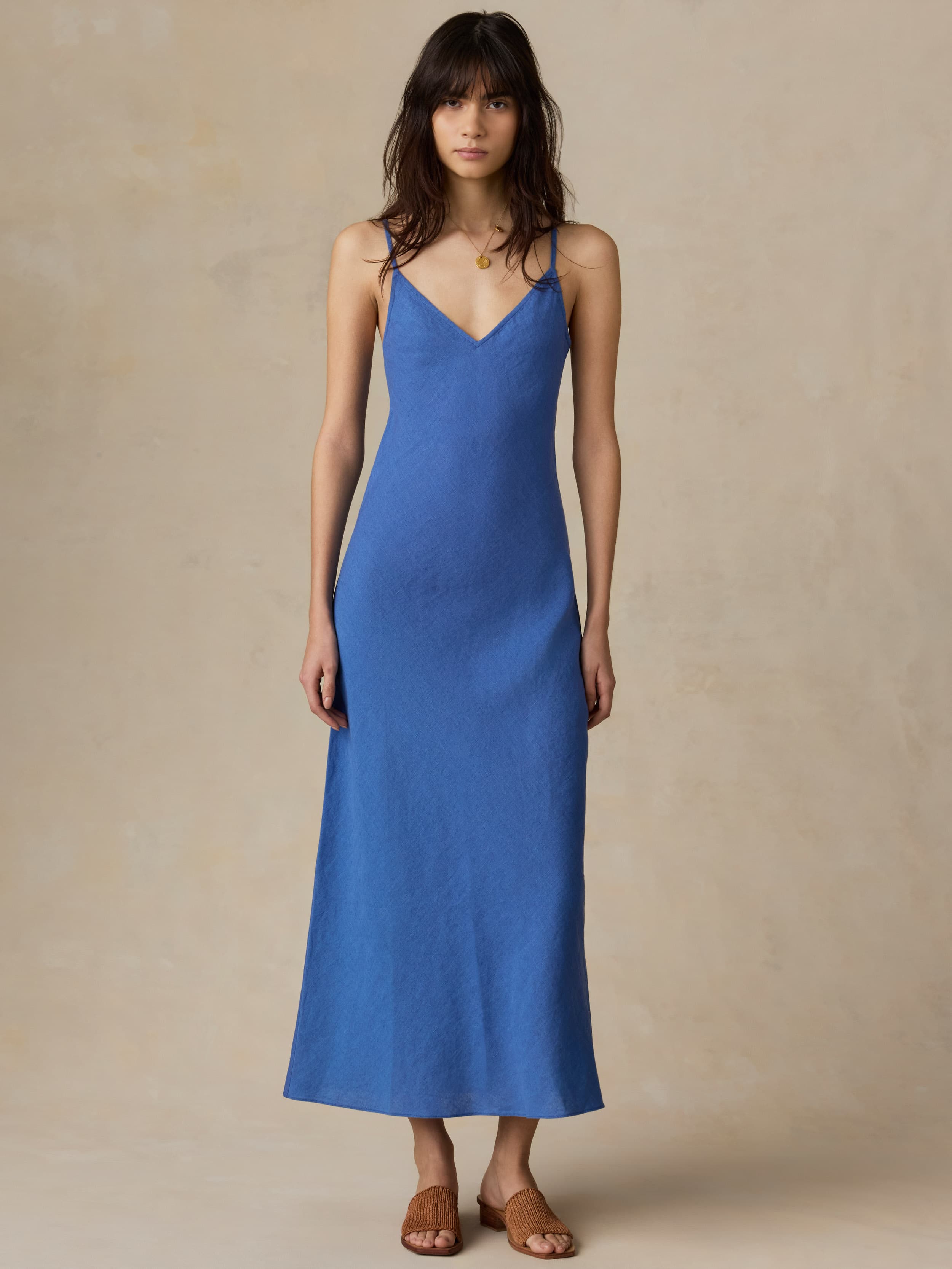 Woman wearing a blue slip dress against a beige background