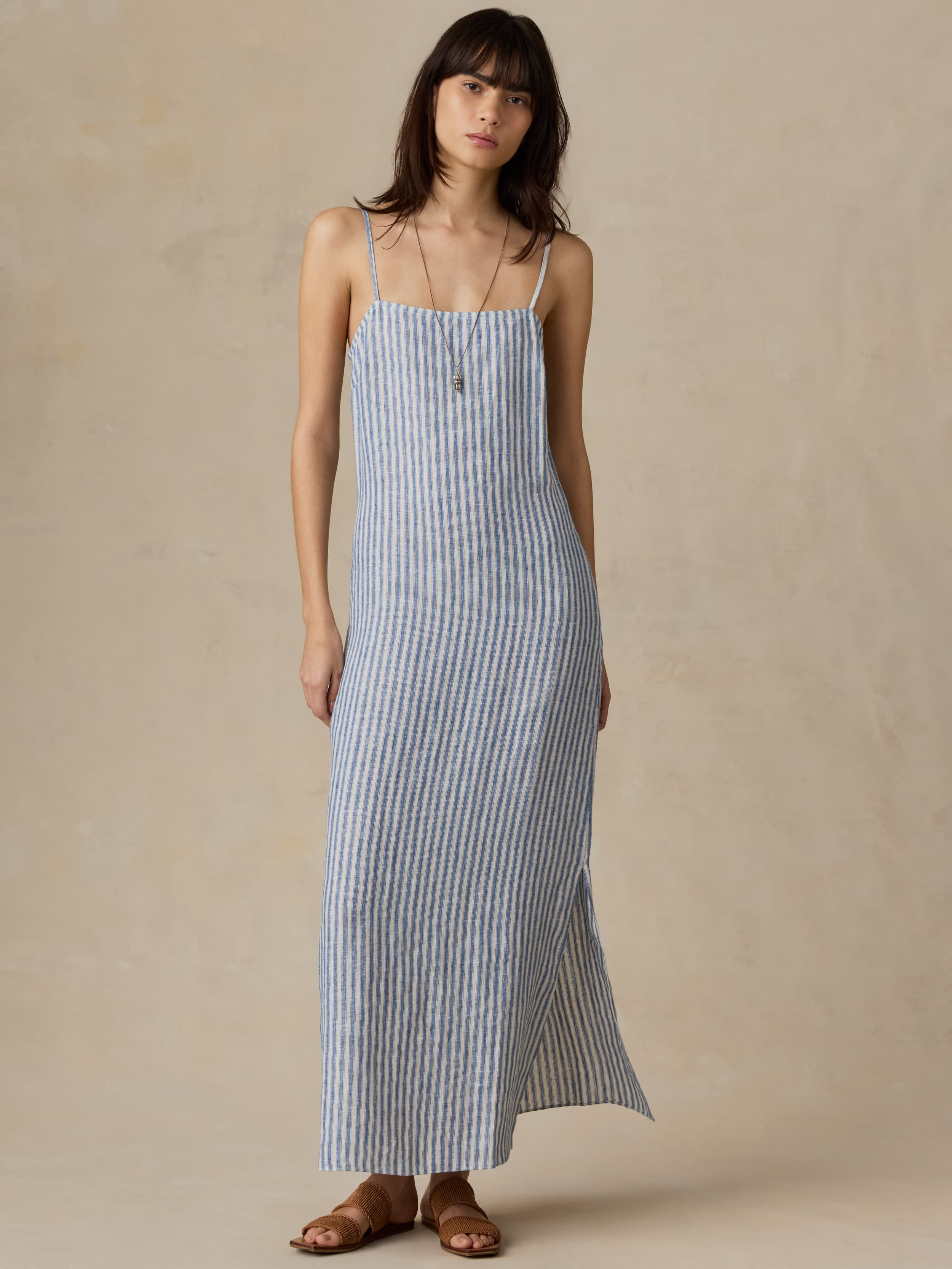 Woman wearing a blue and white striped dress on a beige background