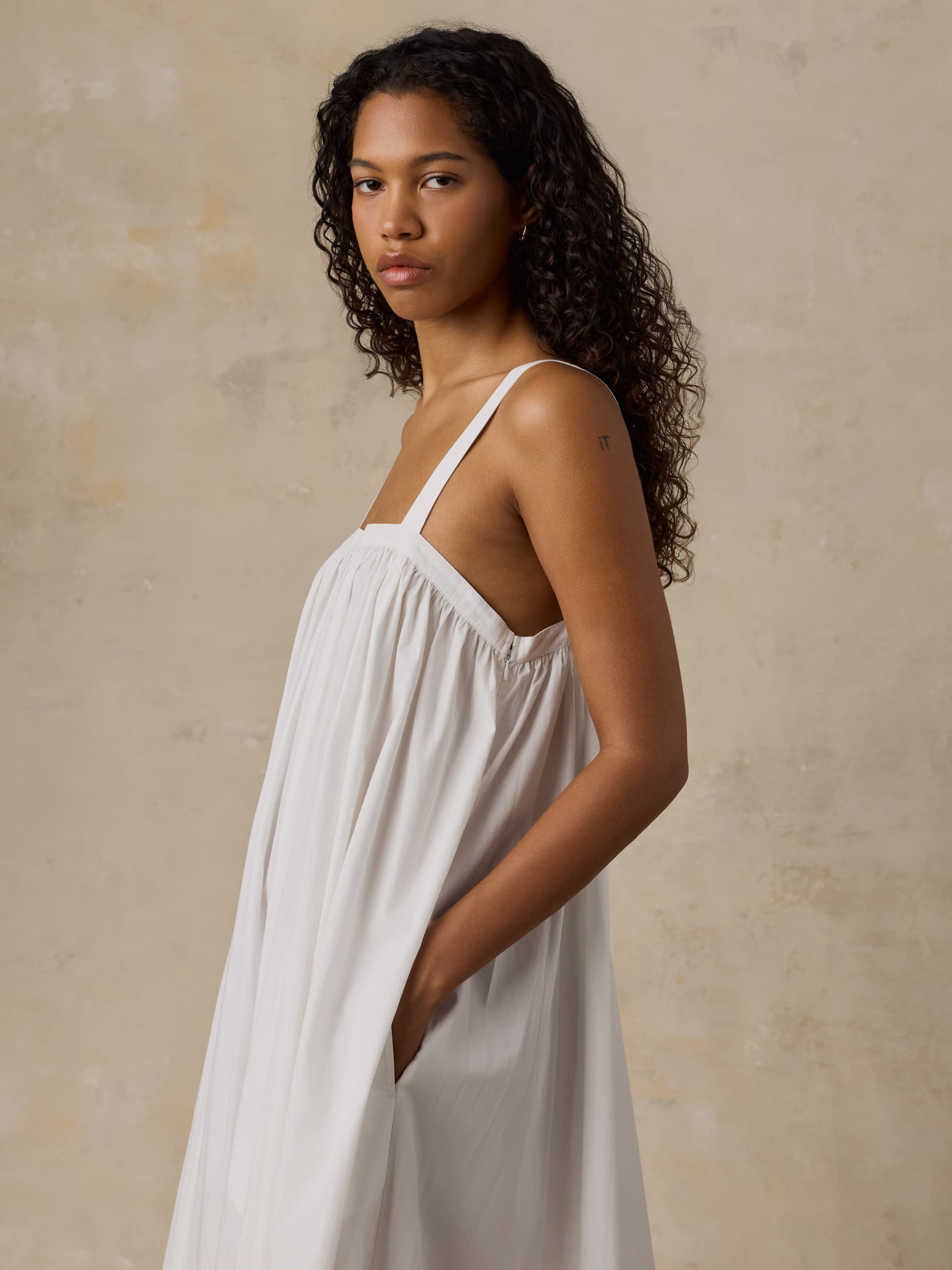 Woman wearing a white dress against a beige background