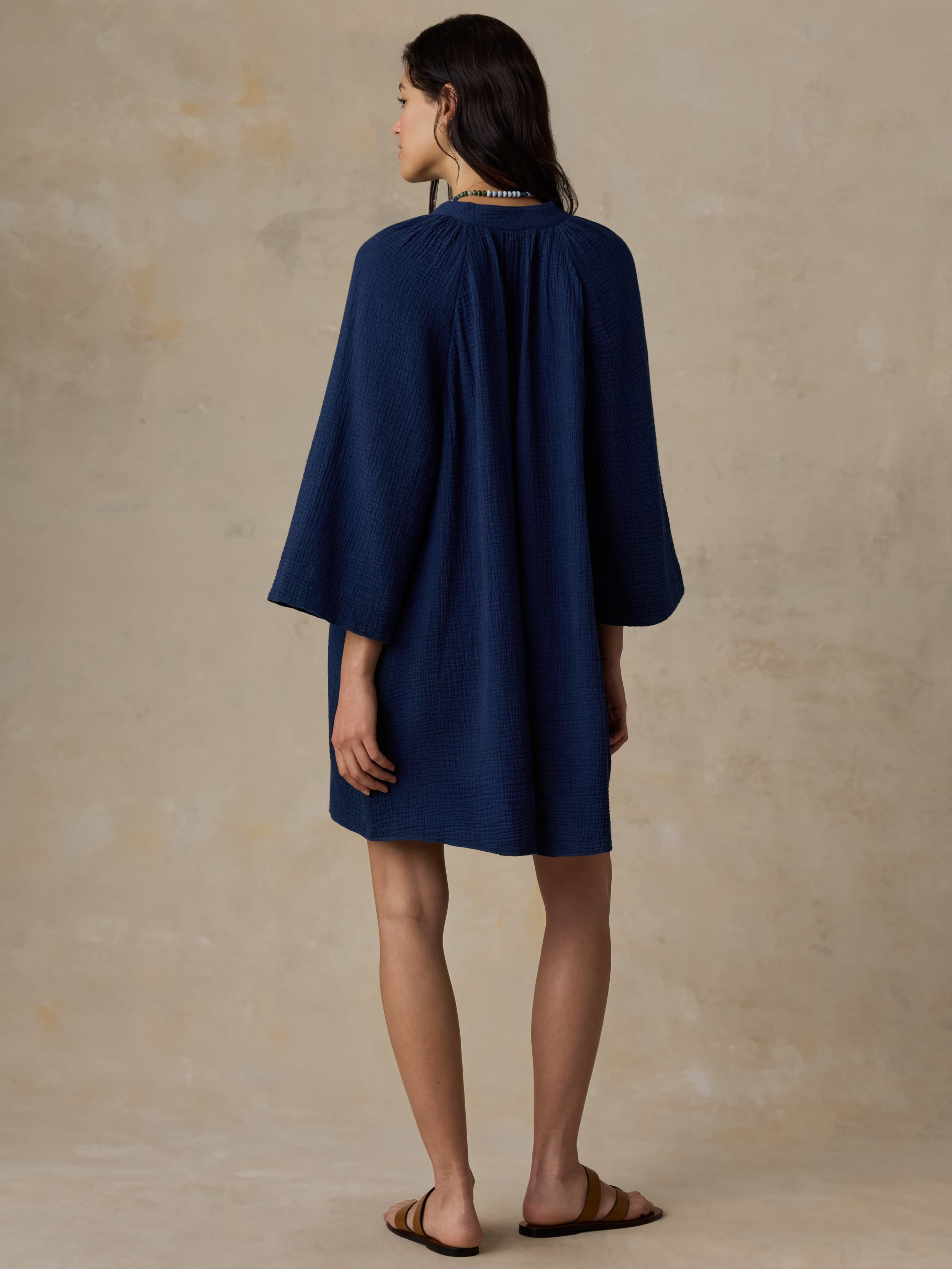 Woman wearing a blue dress against a beige background