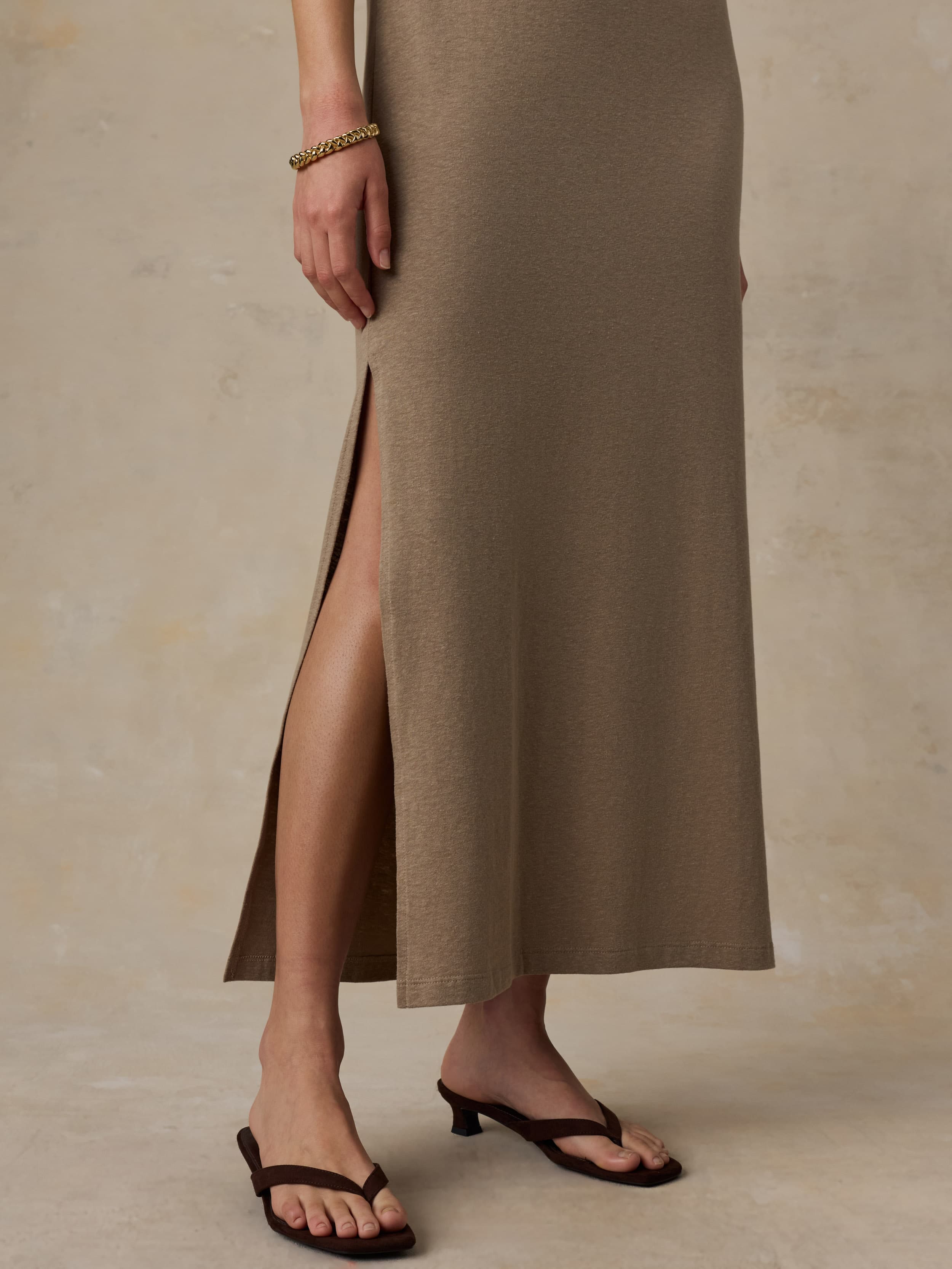 Woman wearing a long beige dress against a neutral background
